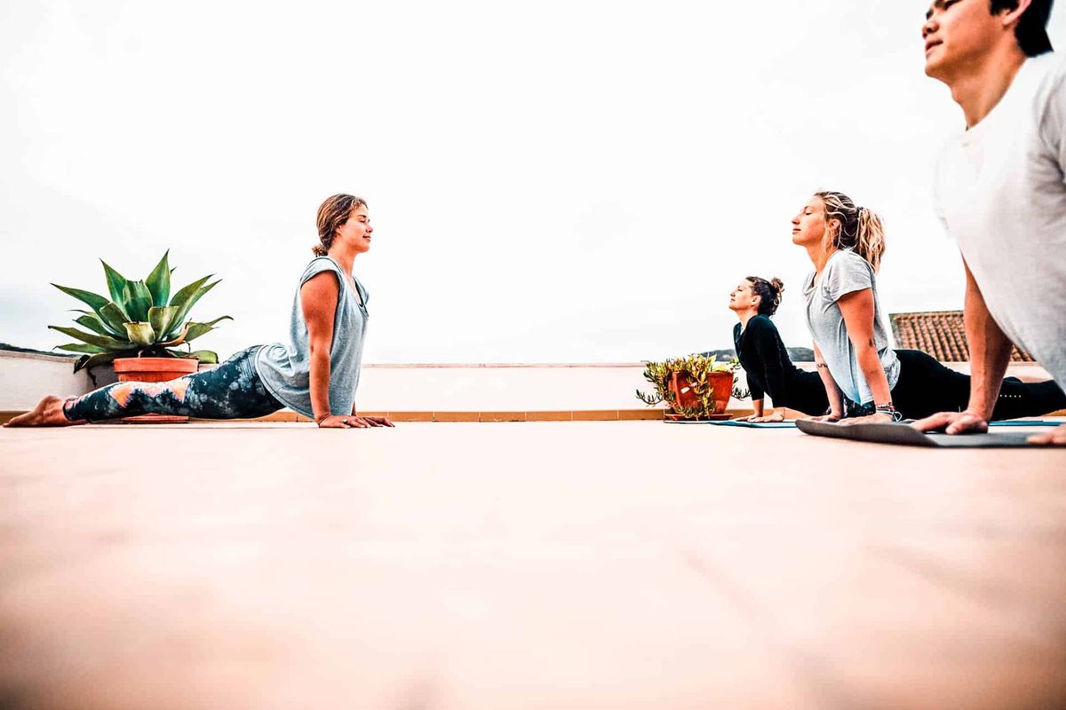 Instructor teaching students to do upward dog Yoga pose.