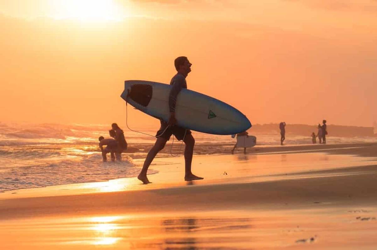 Surfer walking on shore in Canggu at sunset