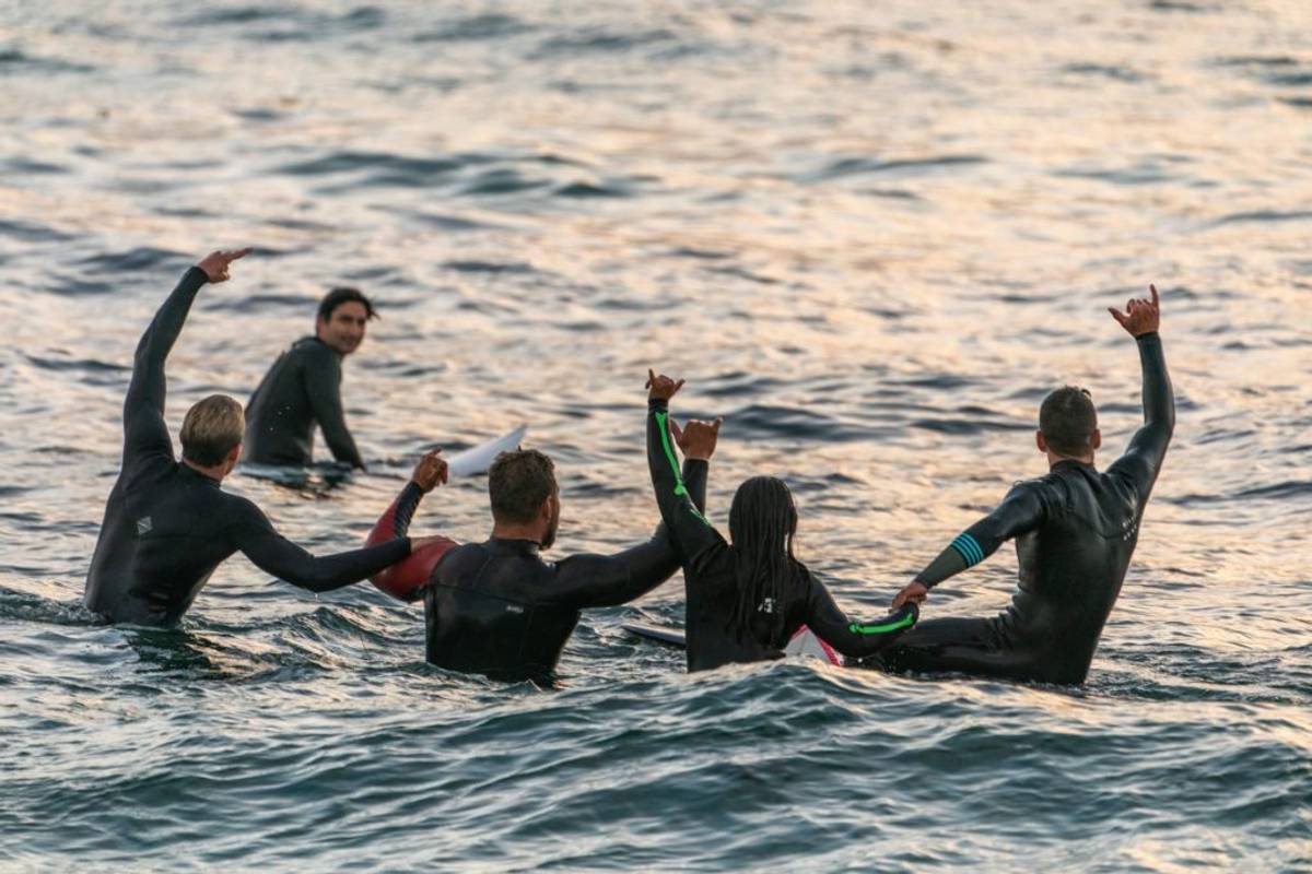 Surfers linking hands in the water