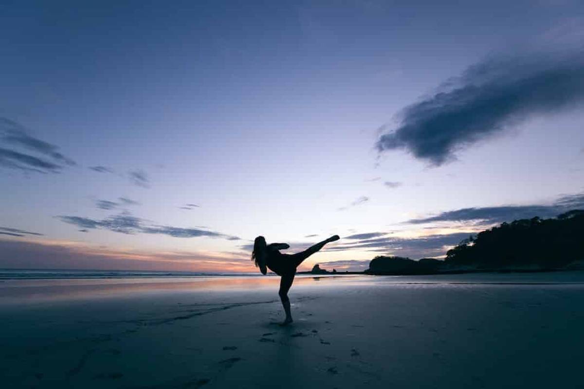 Girl exercising on the shore at sunset