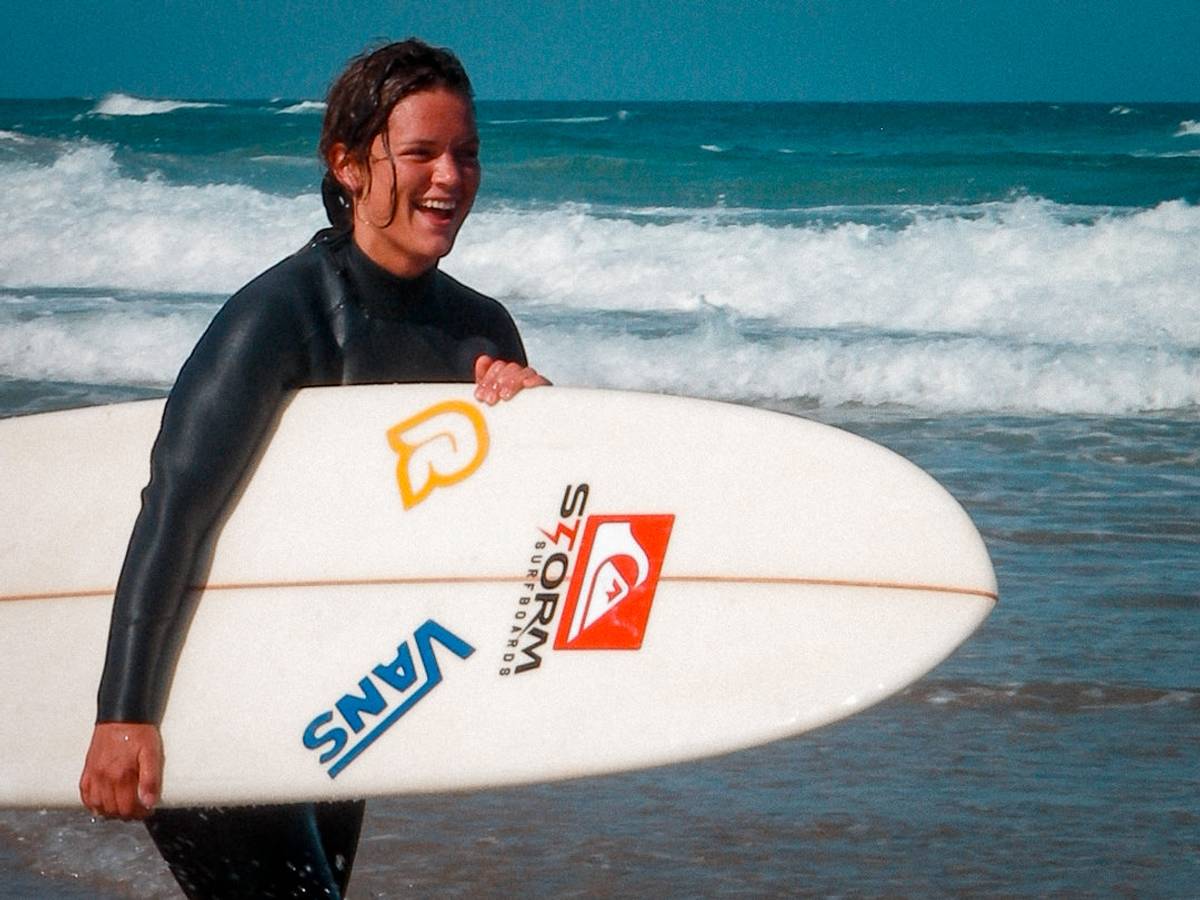 3 beginner surfers holding their board