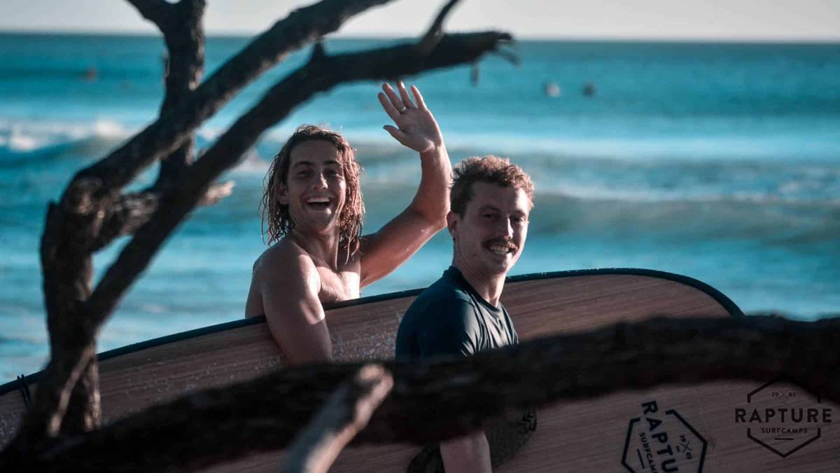 An image of two surfers smiling