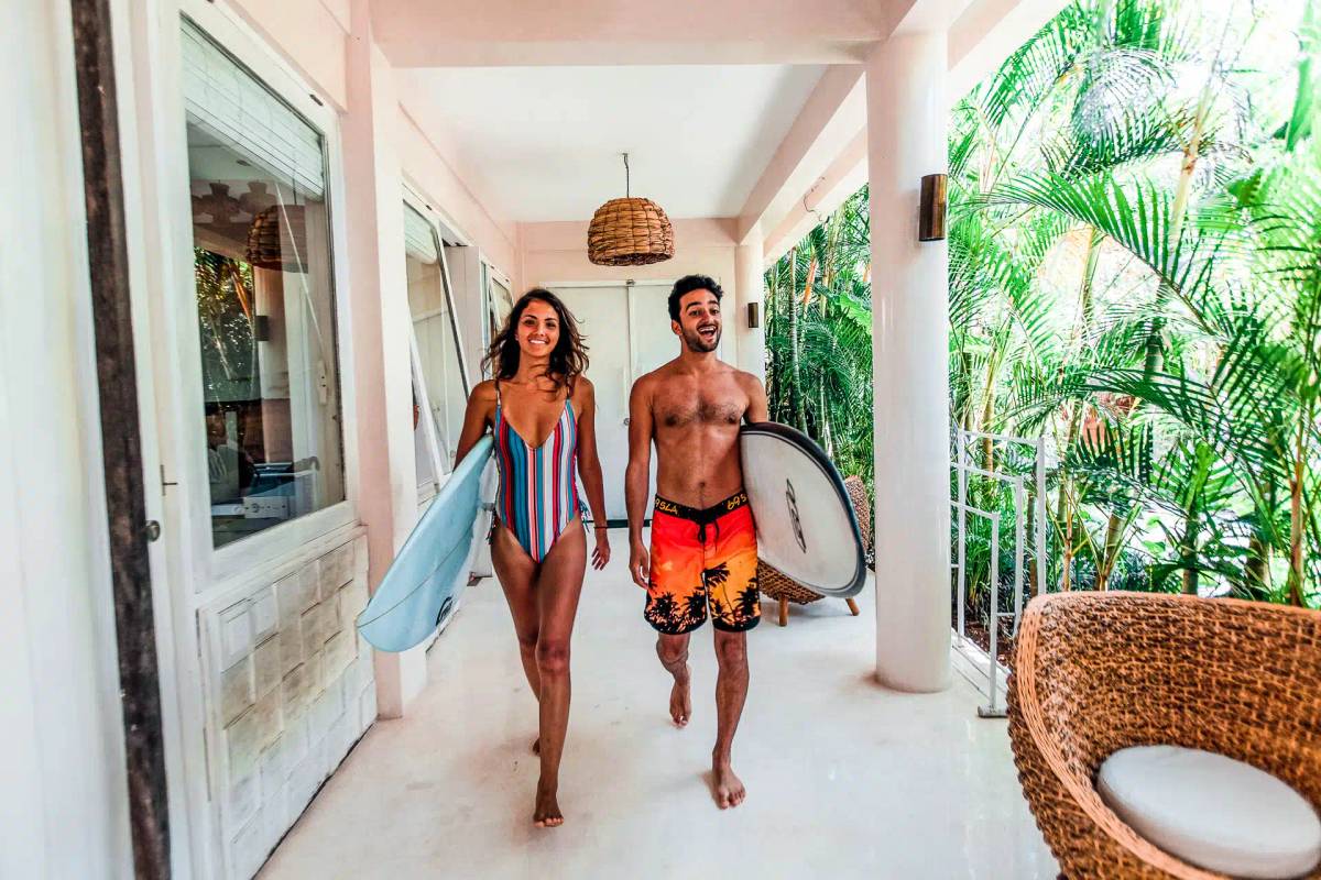 Two people walking with surfboards in their hands
