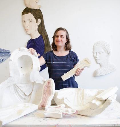 Portraitfoto der Künstlerin Isabel Ritter, vor ihr Teile ihrer Skulpturen