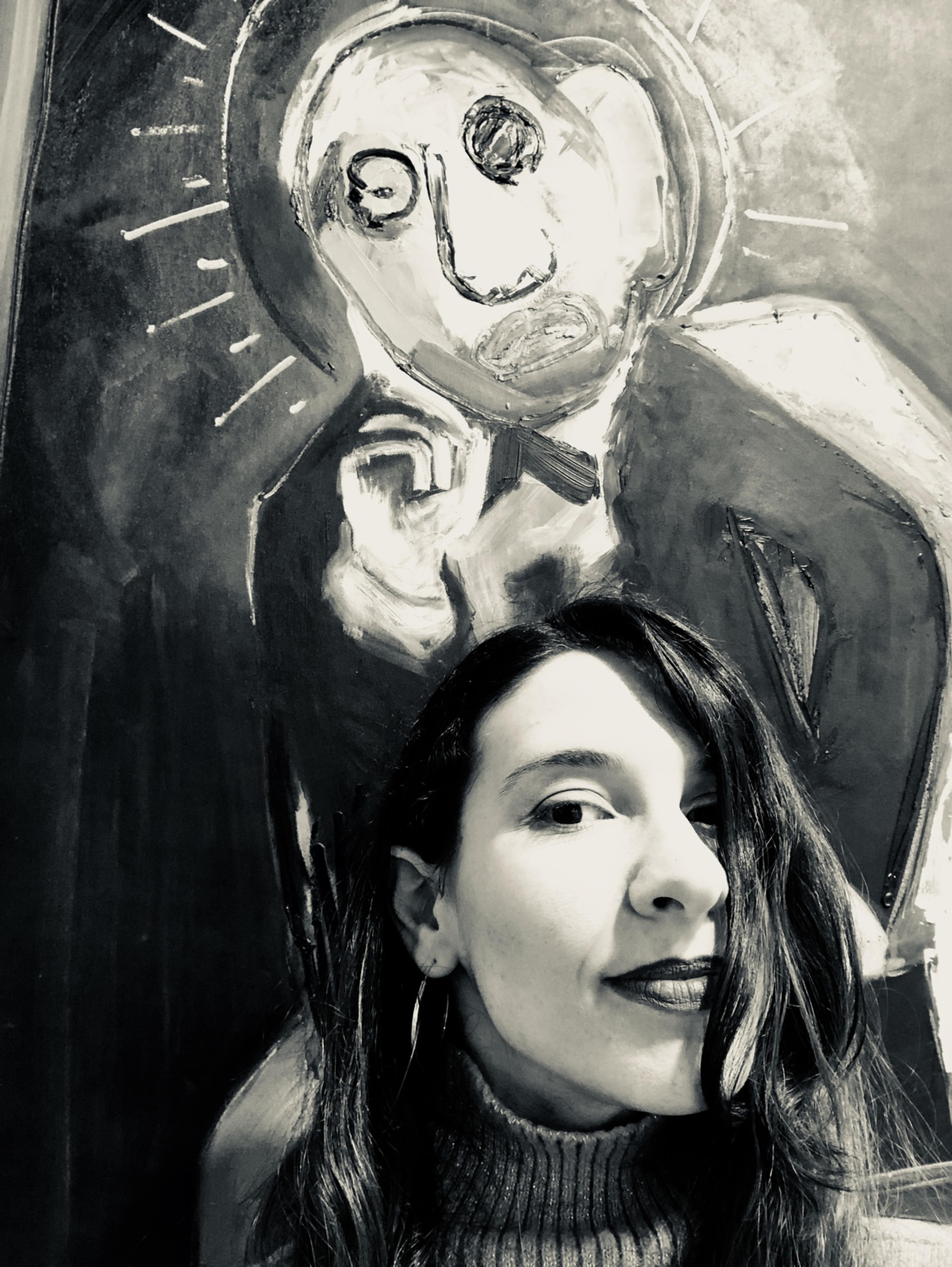 Schwarz weiß Portrait der Künstlerin Penny Monogiou, vor einem ihrer Bilder