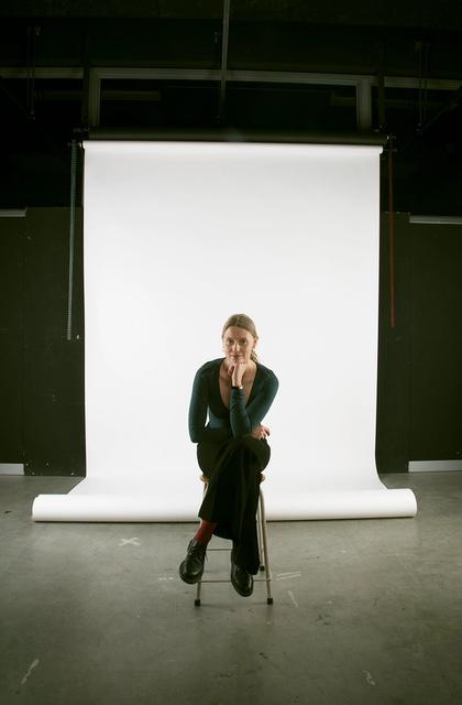 Portraitfoto Theresa Maria Forthaus, junge Frau auf einem Hocker vor einer weißen Leinwand