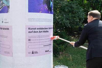 Hamburgs Kultursenator Carsten Brosda beendet symbolisch die letzte Kunstplakatierung an einer Litfaßsäule.