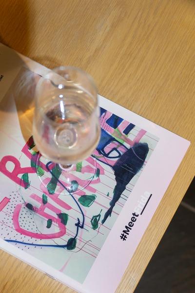 Ein Glas Wein auf einem Ausstellungskatalog von MeetFrida, Joséphine Sagna