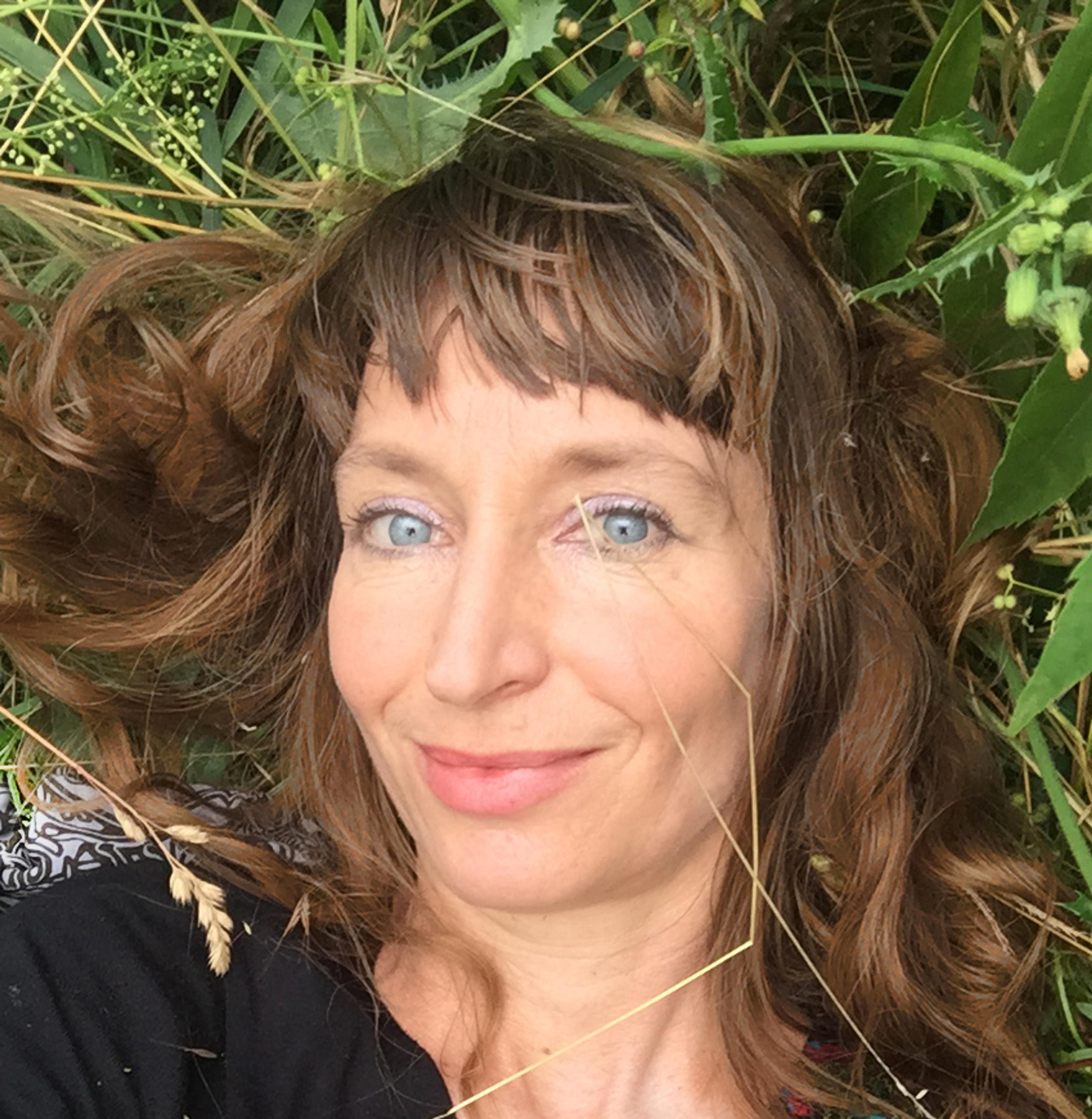 Portraitfoto der Künstlerin Eva Lippert, liegend im Gras