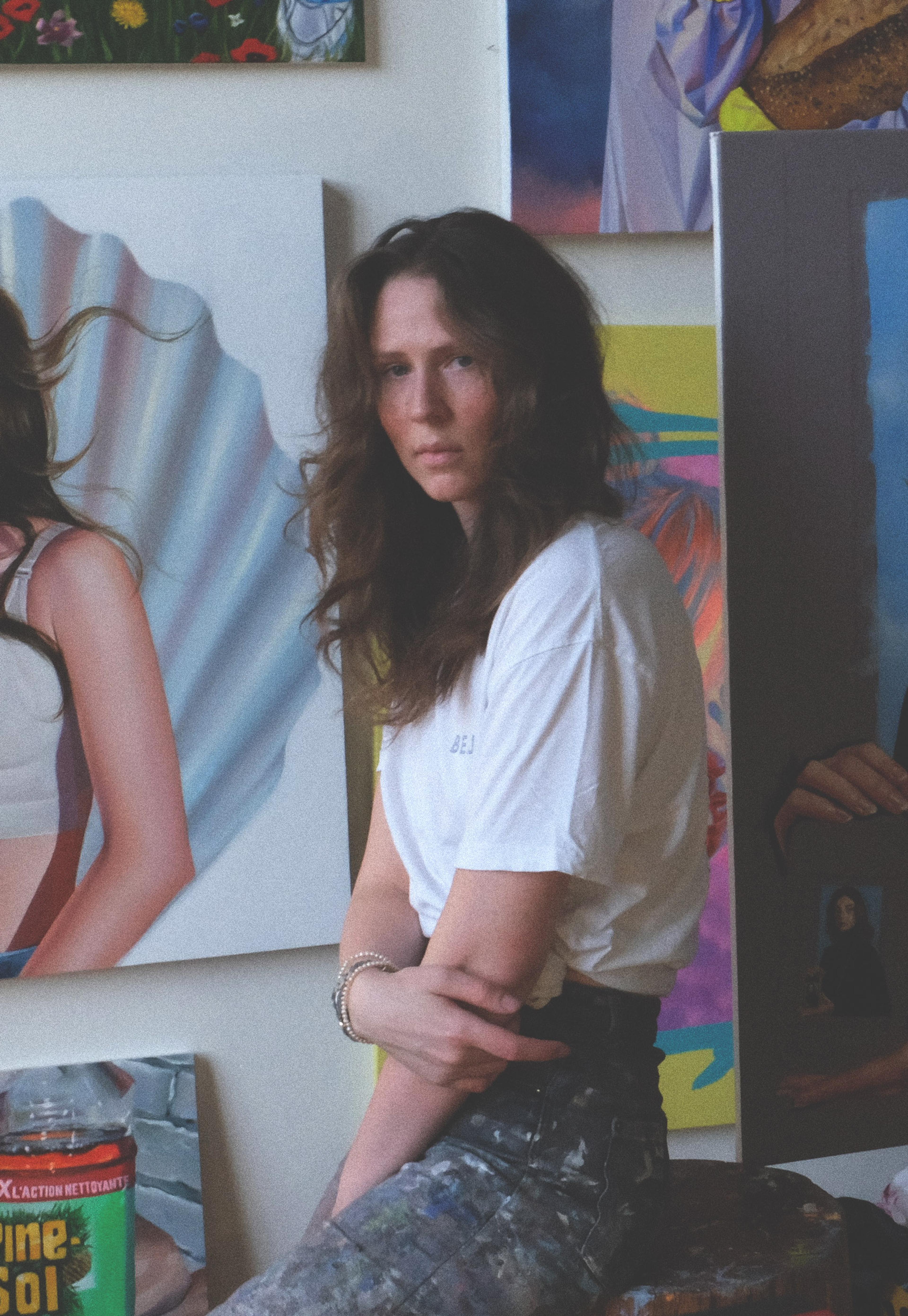 Portraitfoto der Künstlerin Roxanne Suariol, in ihrem Studio, vor figurativen Malereien