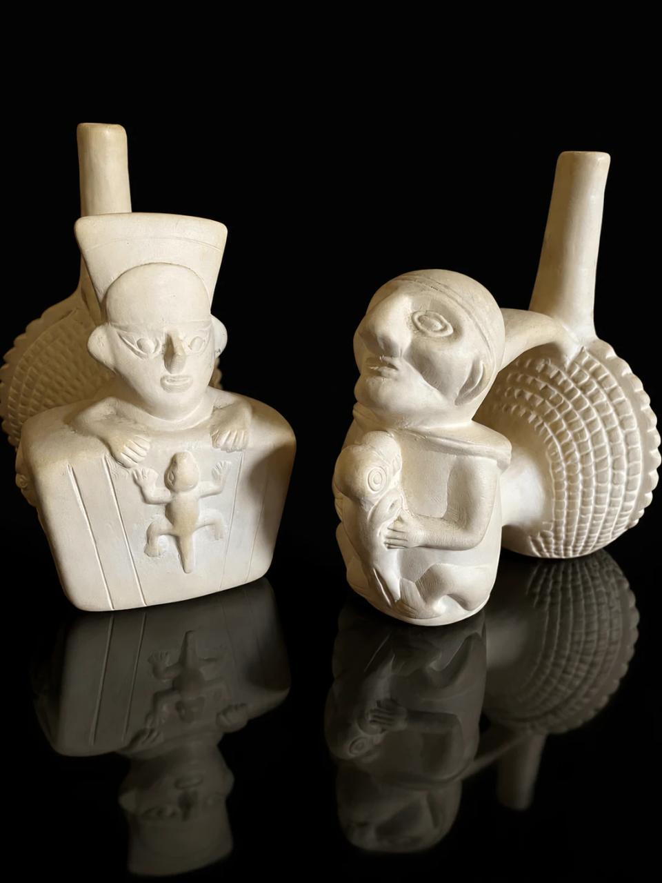 Three Peruvian ceramic whistles on a glossy black surface.