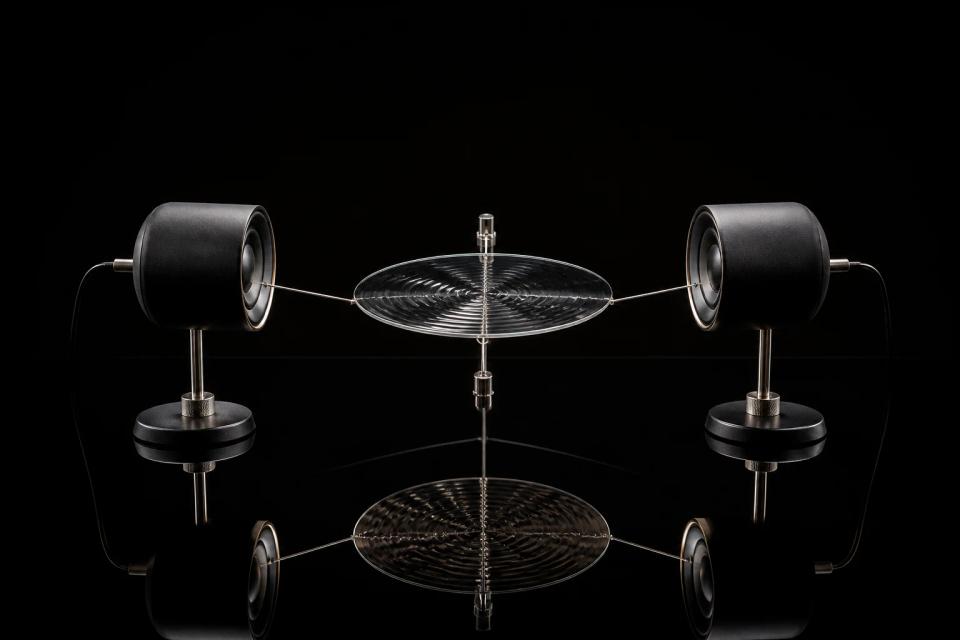 Two acoustic transducers facing a rippling metal membrane.