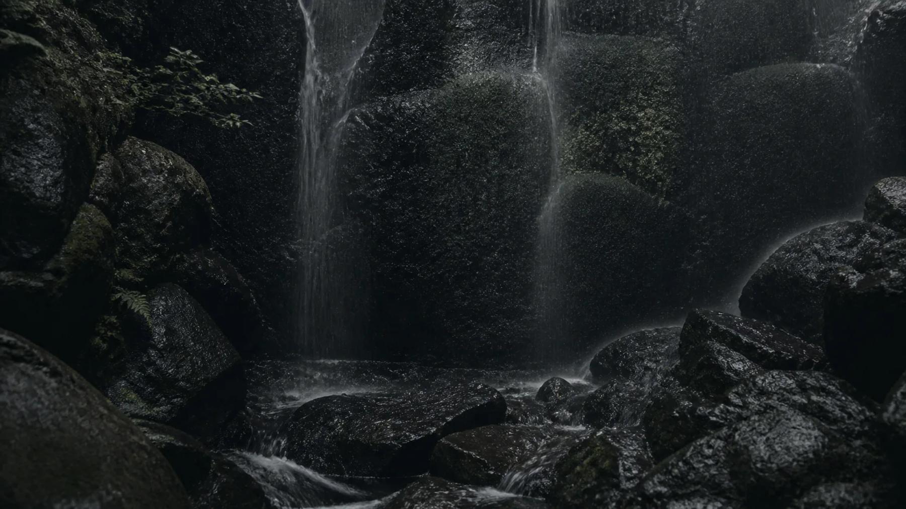 Water cascading quietly over dark stone.