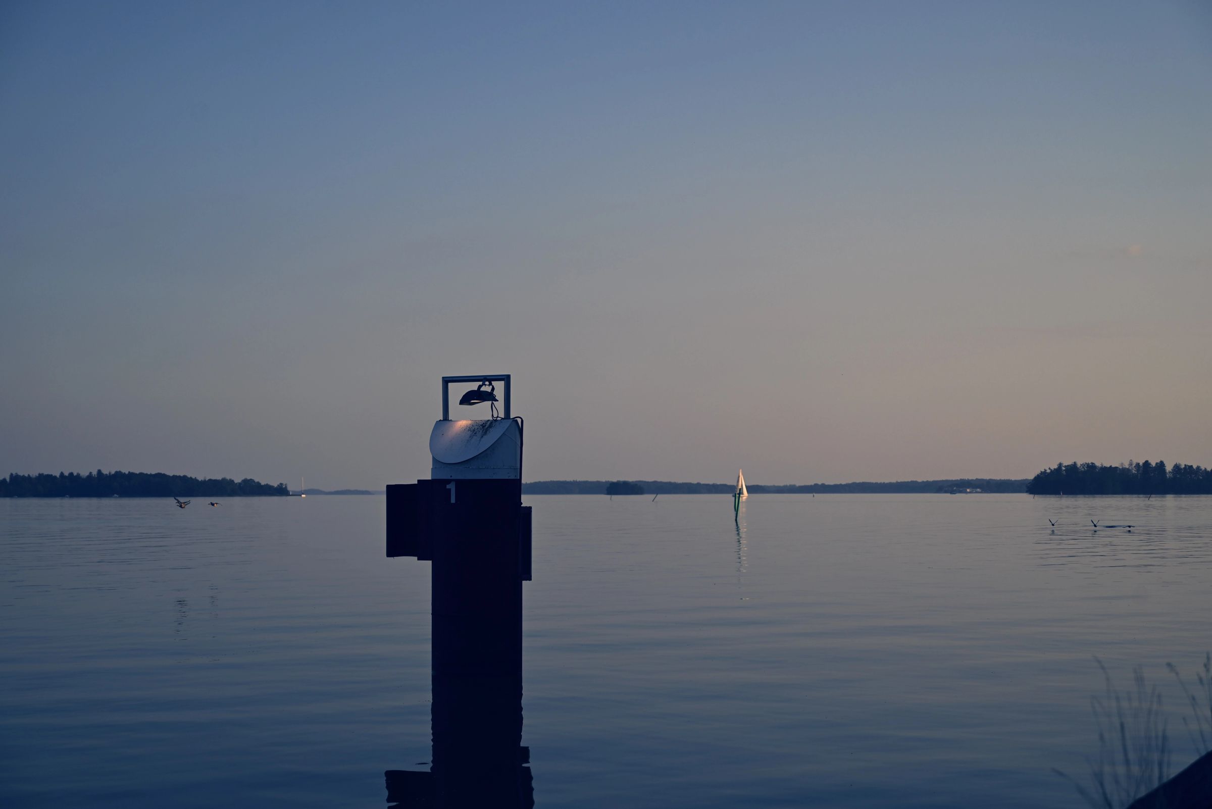 Lake Mälaren view during sunset, with perfectly calm waters and boat traversing the horizon
