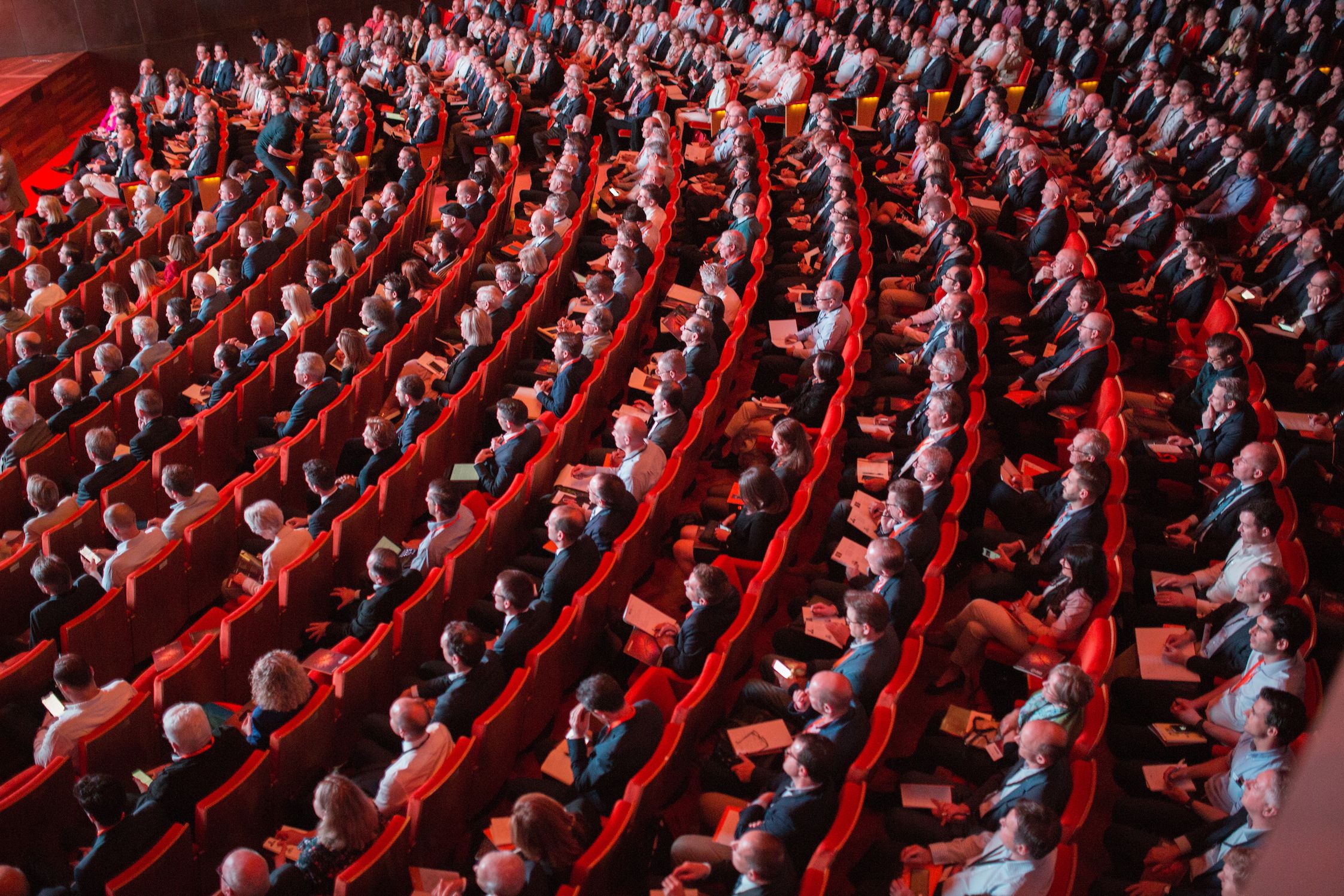 Photo of conference atttendees in red seats