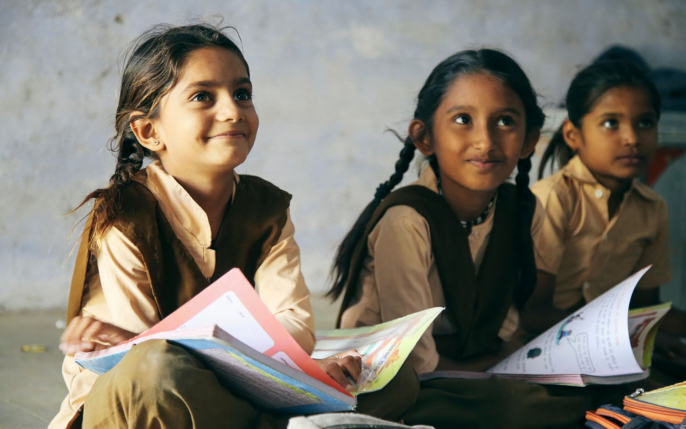 Smiling girls in school uniform with books