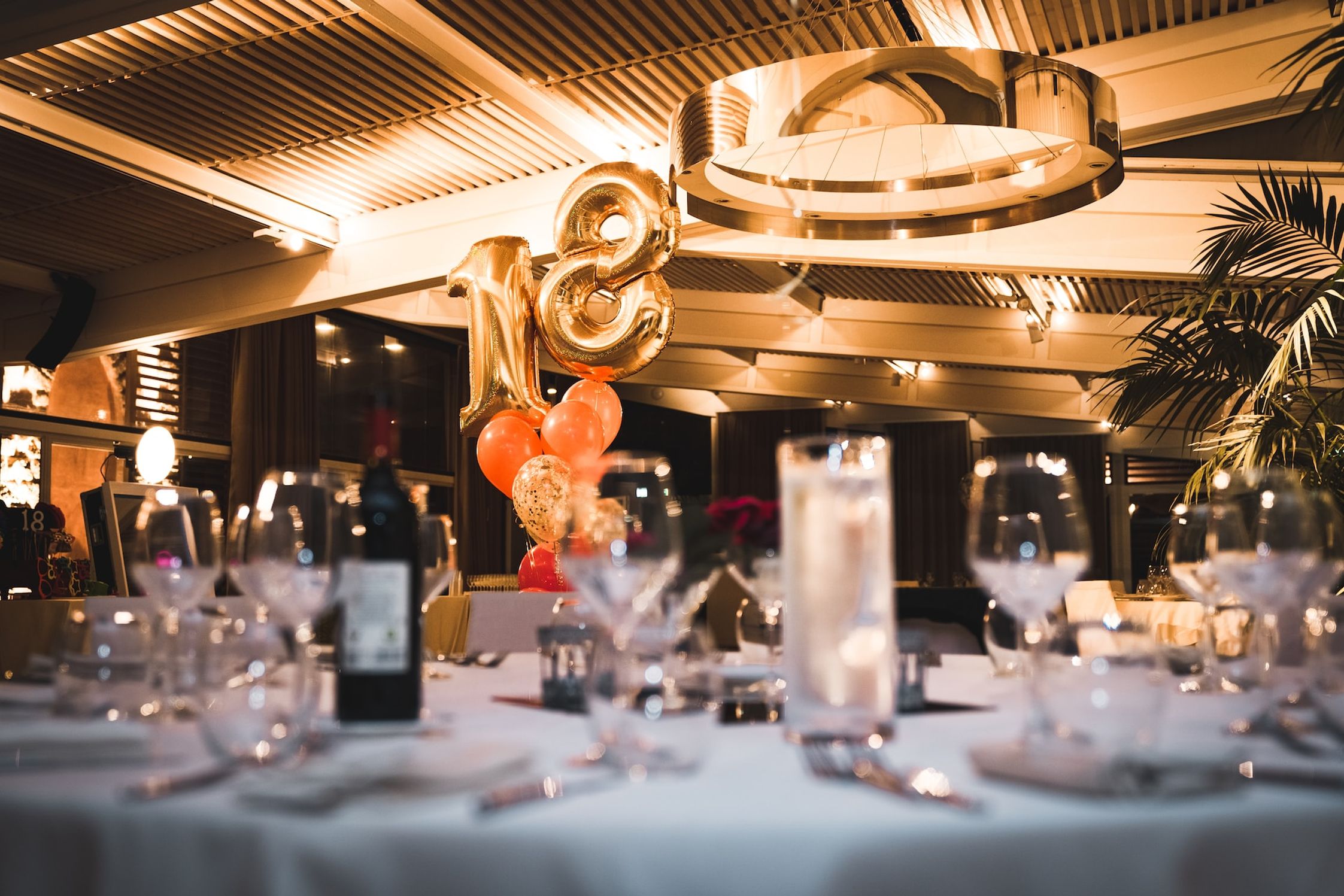 An 18th birthday party table setting with glasses out of focus in the foreground