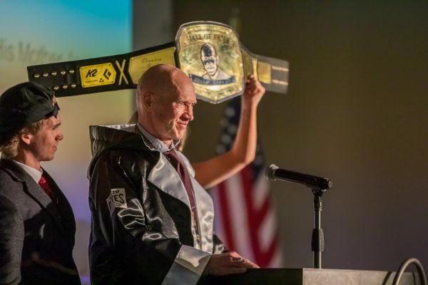 Someone being awarded a gold wrestling belt award on stage