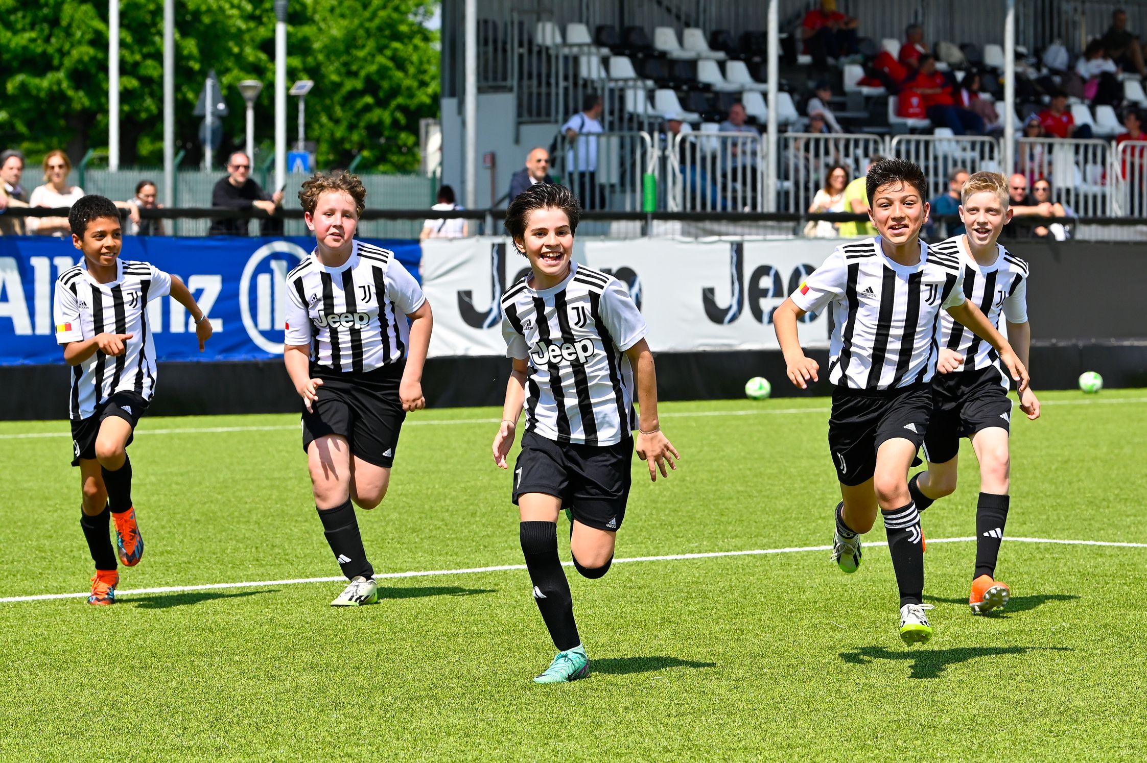 Boys running and smiling on the football pitch in black and white stripe football jerseys