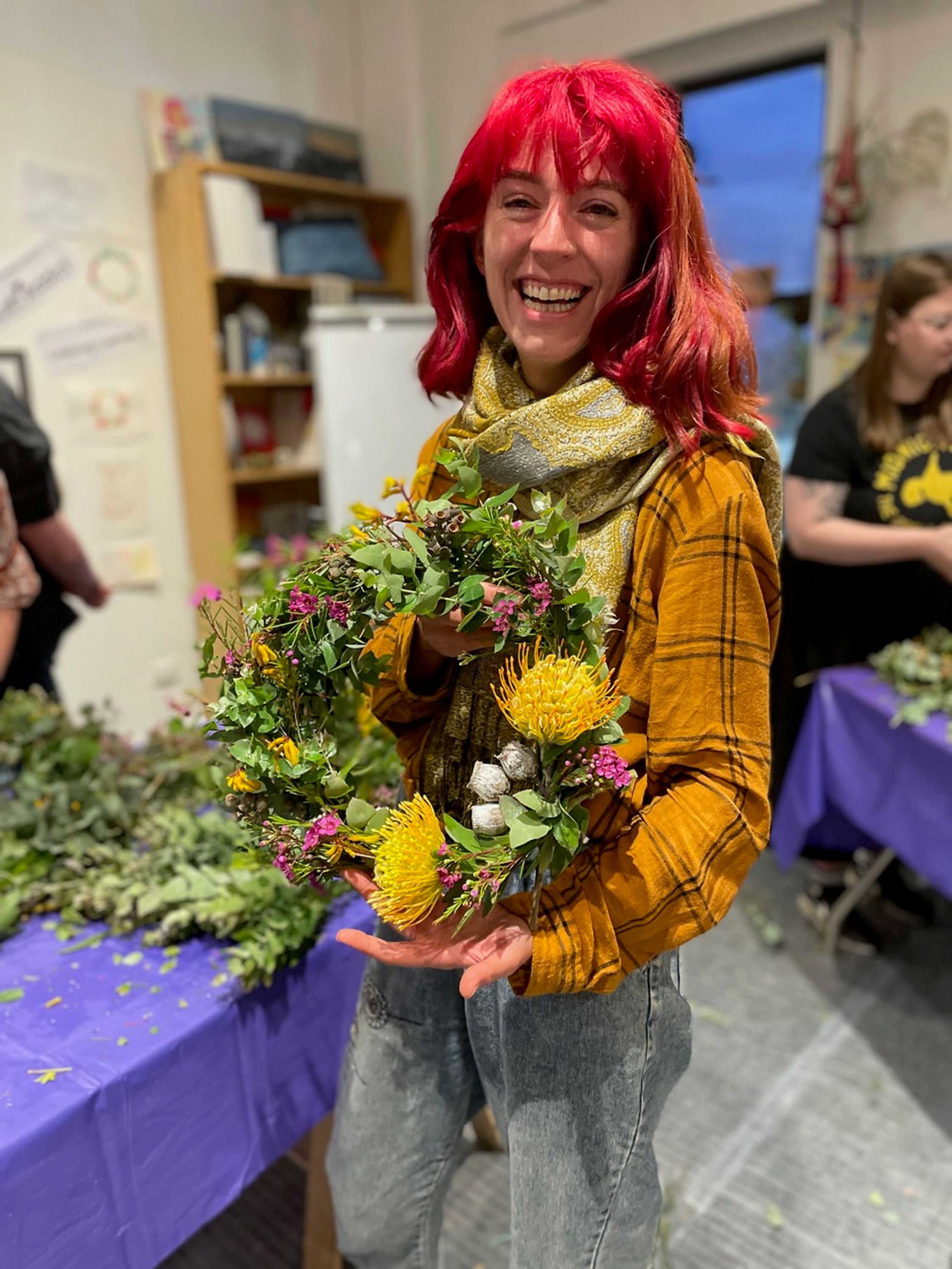 A smiling student holidng a flower wreath she has made