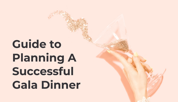 A peachy pink background with a elegant hand holding a cocktail glass that is spilling some dazzling glitter! Title reads 'Guide to Planning a Successful Gala Dinner'