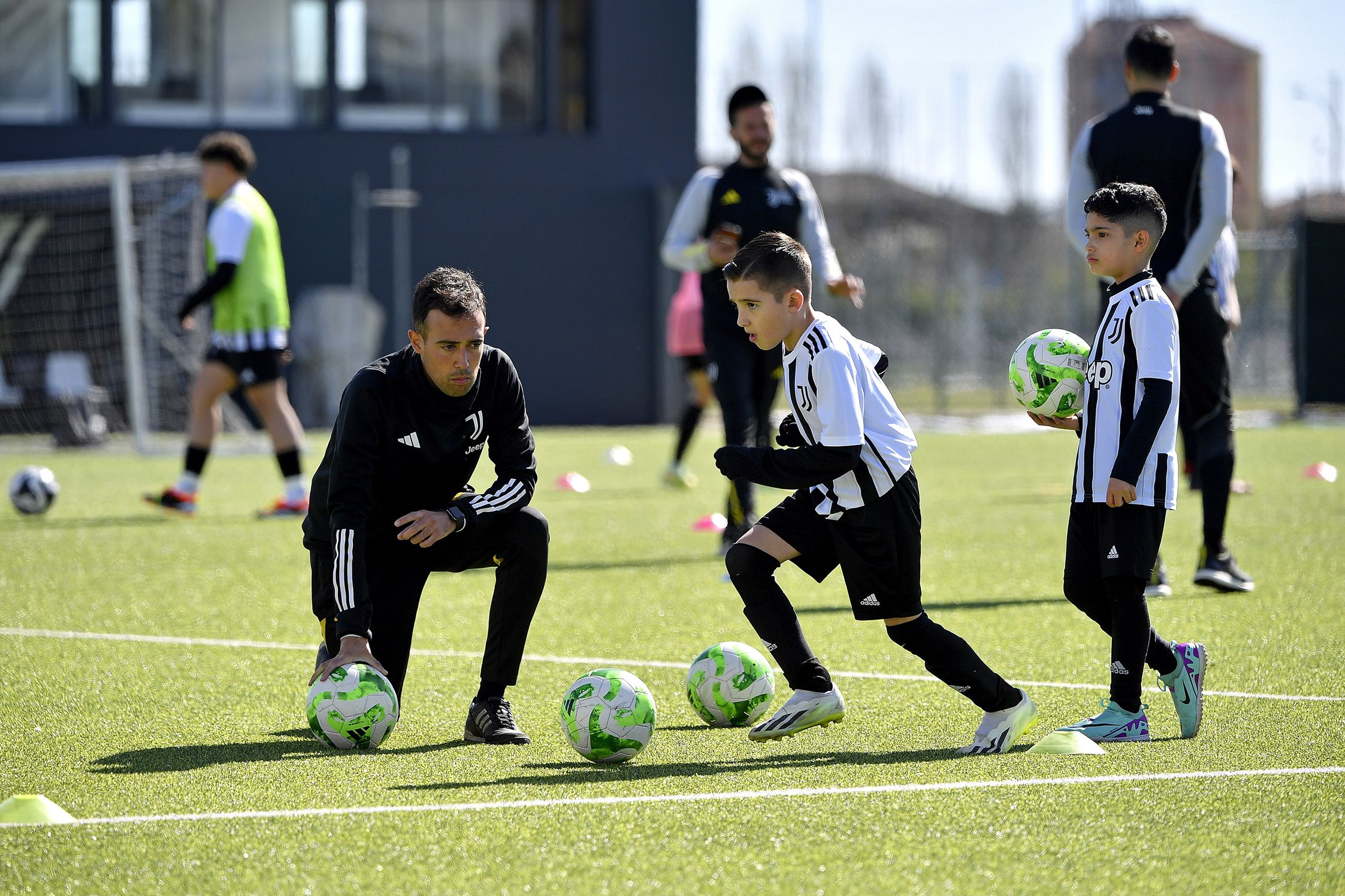 A coach with two kids practising with football