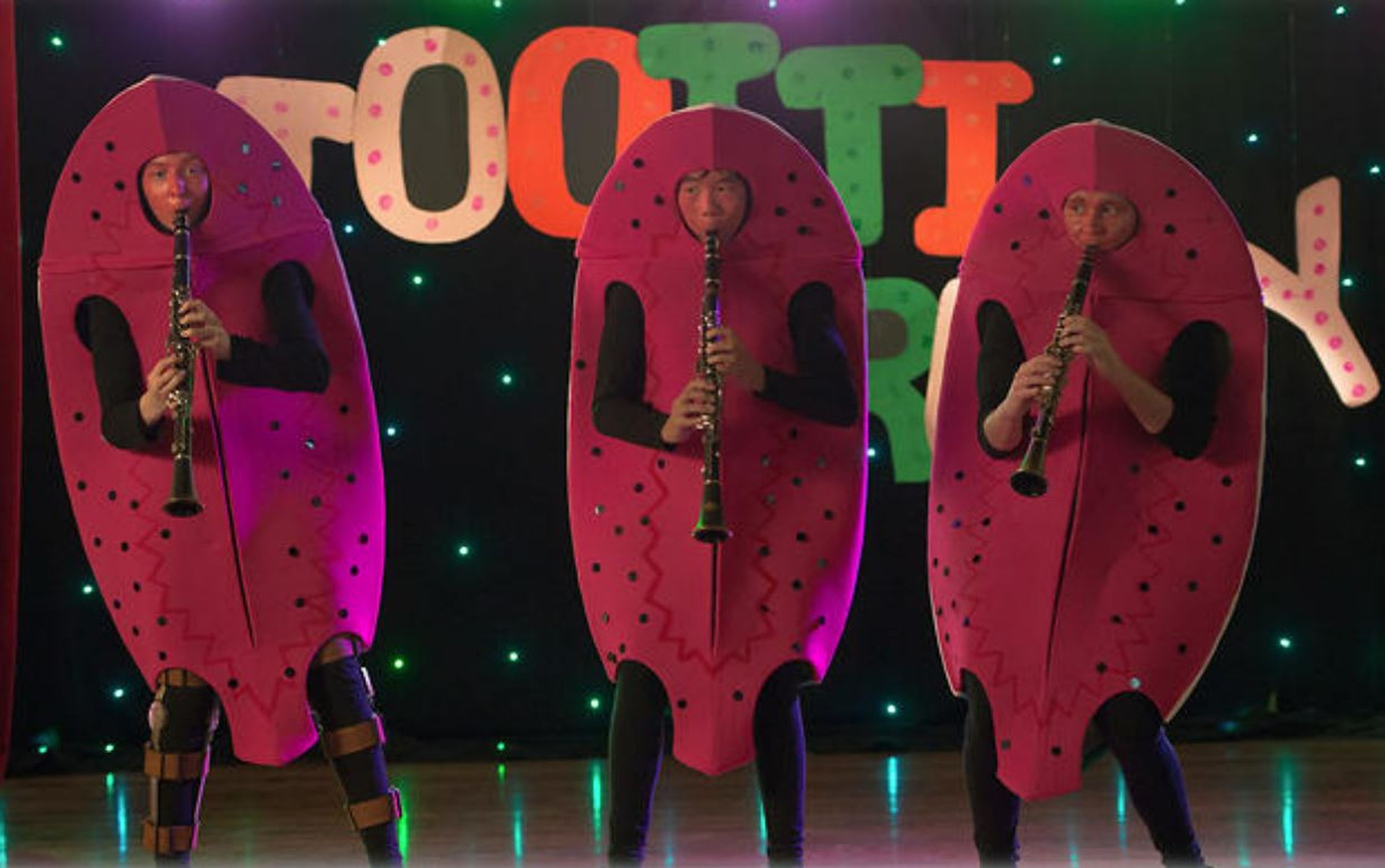 This image is from SBS showing three decoratively dresses students performing at a talent quest