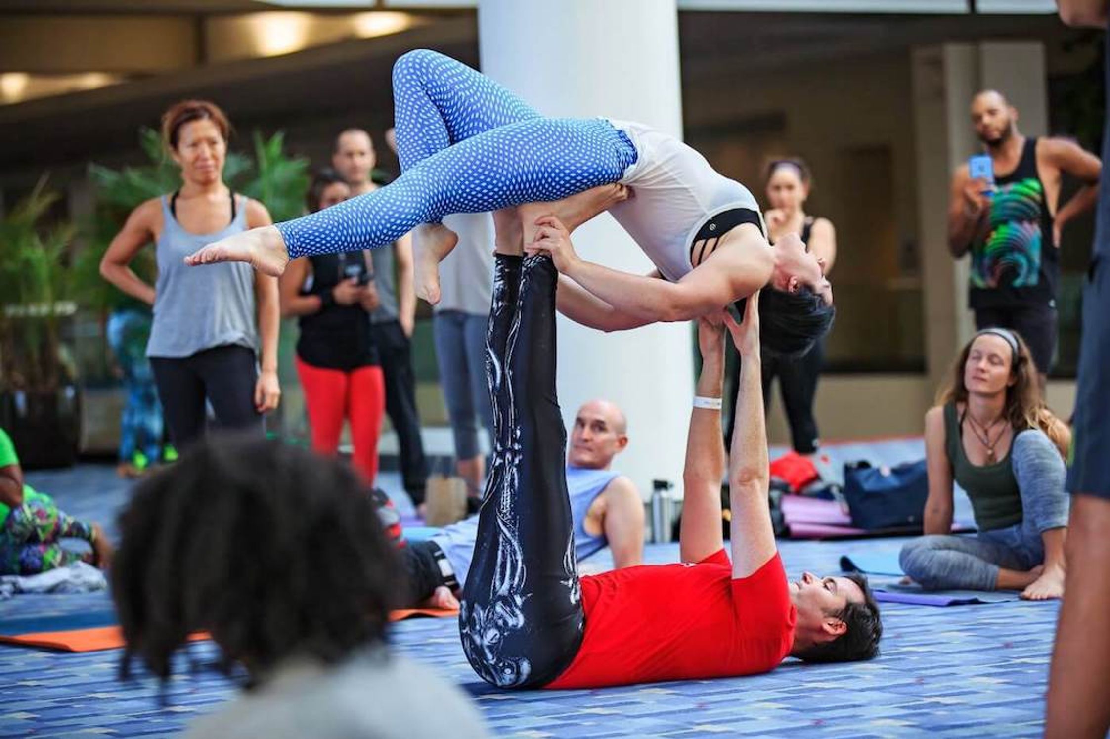A man lying on the floor and supporting a woman in yoga poses