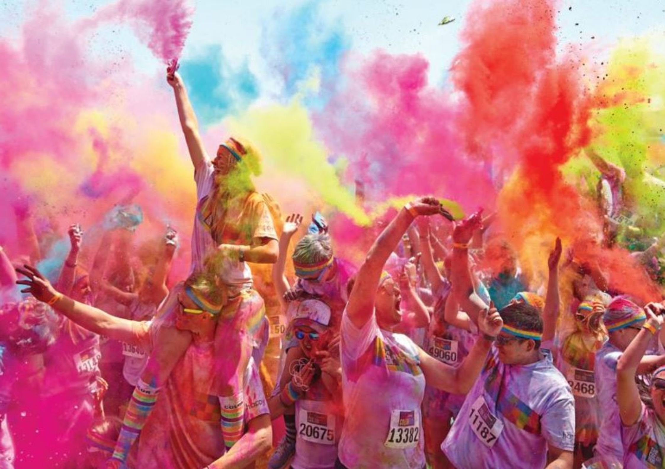 This image is from Saucony, it depicts a group of people at the end of the fun run celebrating with coloured powder