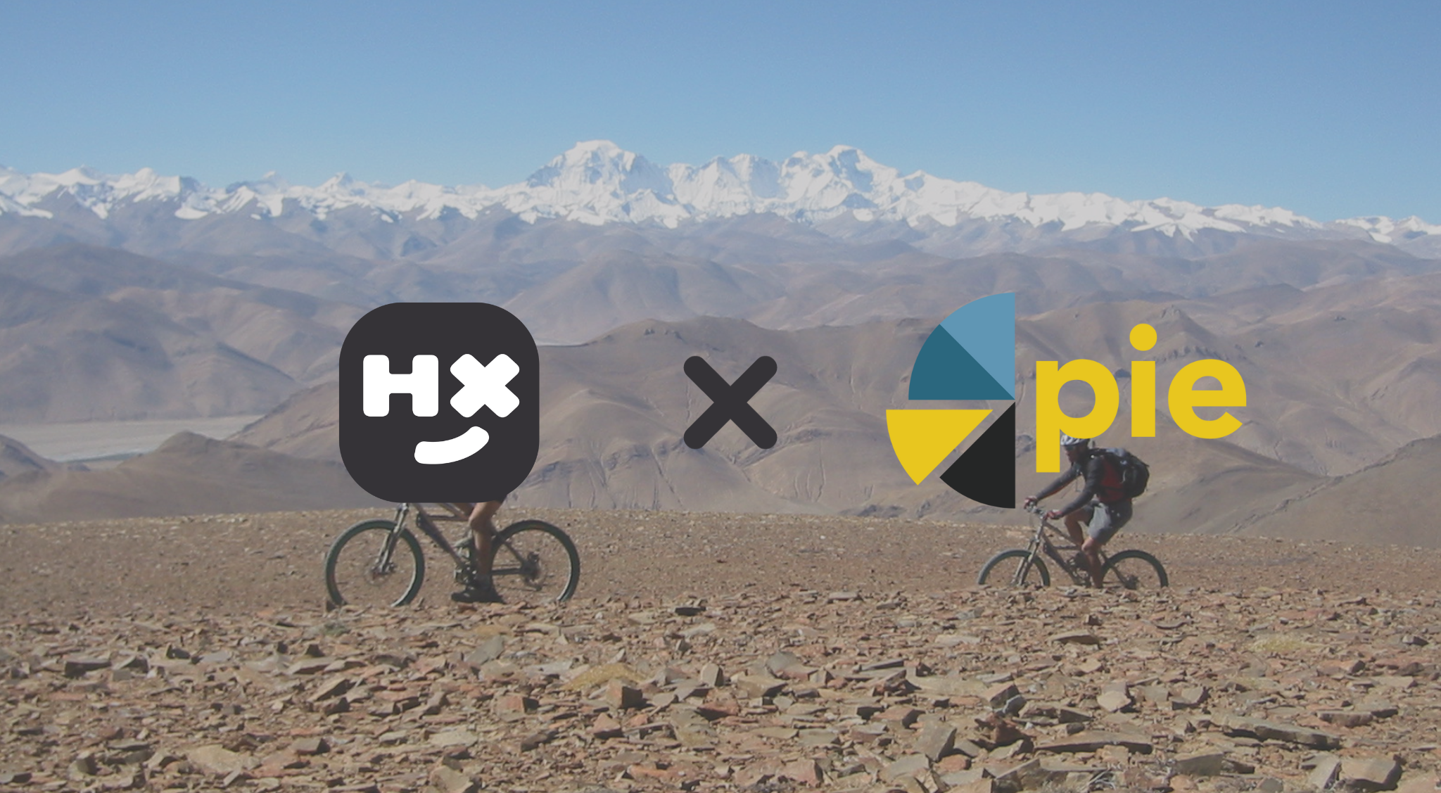 Humanitix favicon and pie logo against the backdrop of two people biking in a mountainous landscape