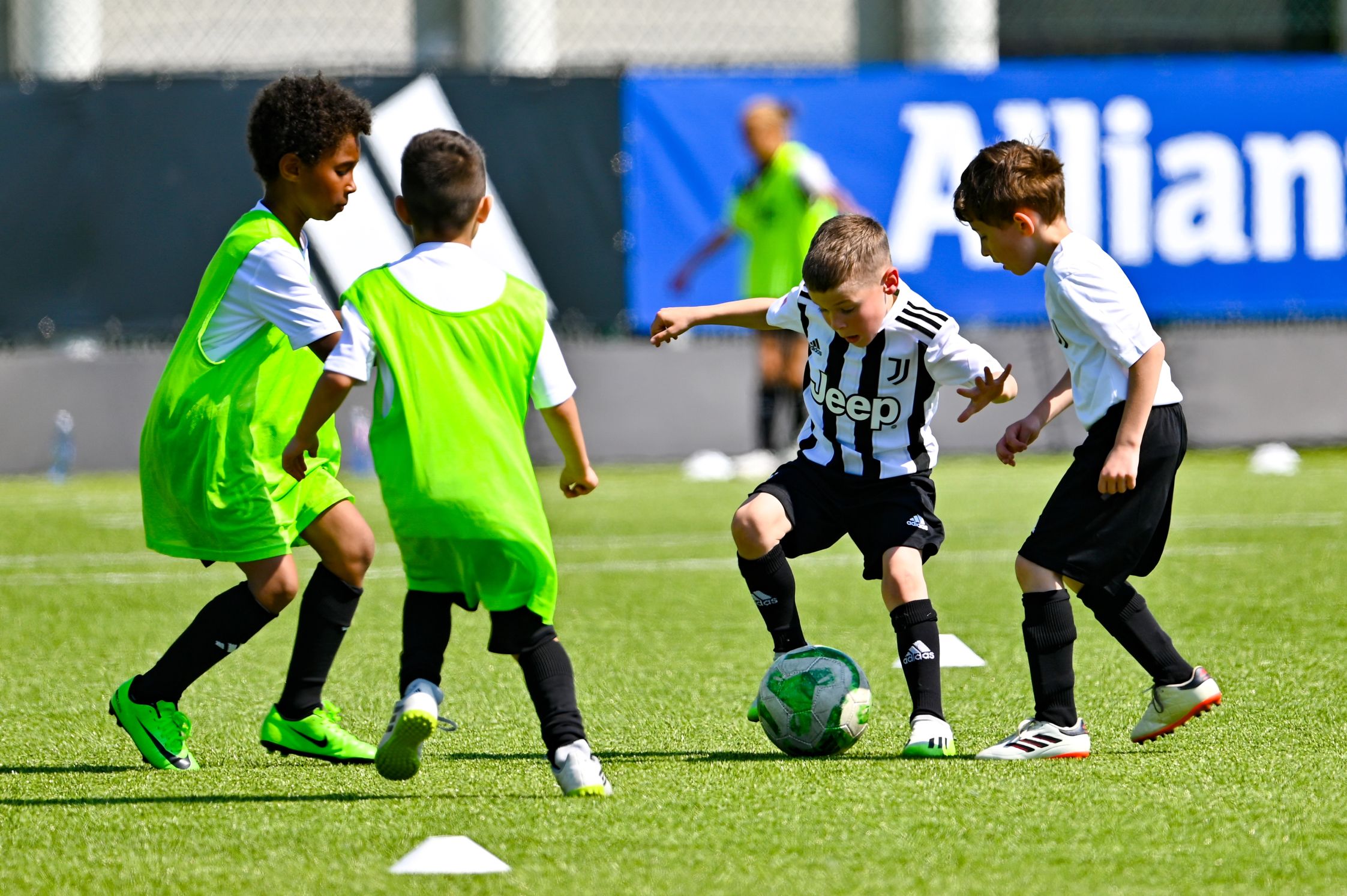Four kids, two in each team, playing football on a green field
