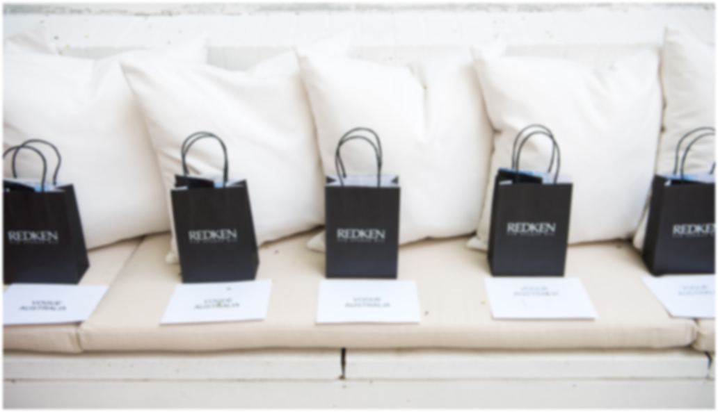 Slightly blurred image of 5 swag bags lined up on a couch 