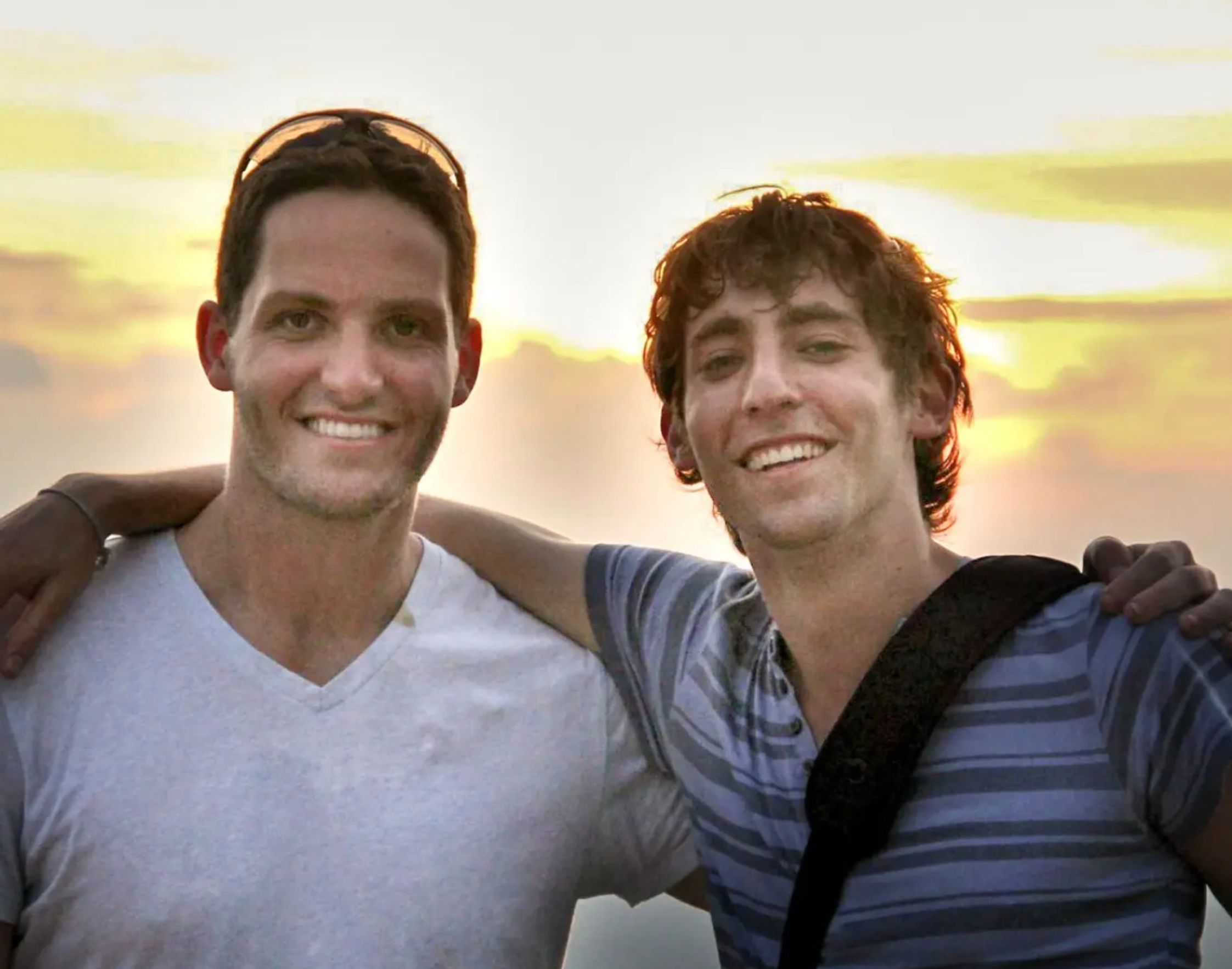 Adam and Josh in their university years, with a sunset in the background