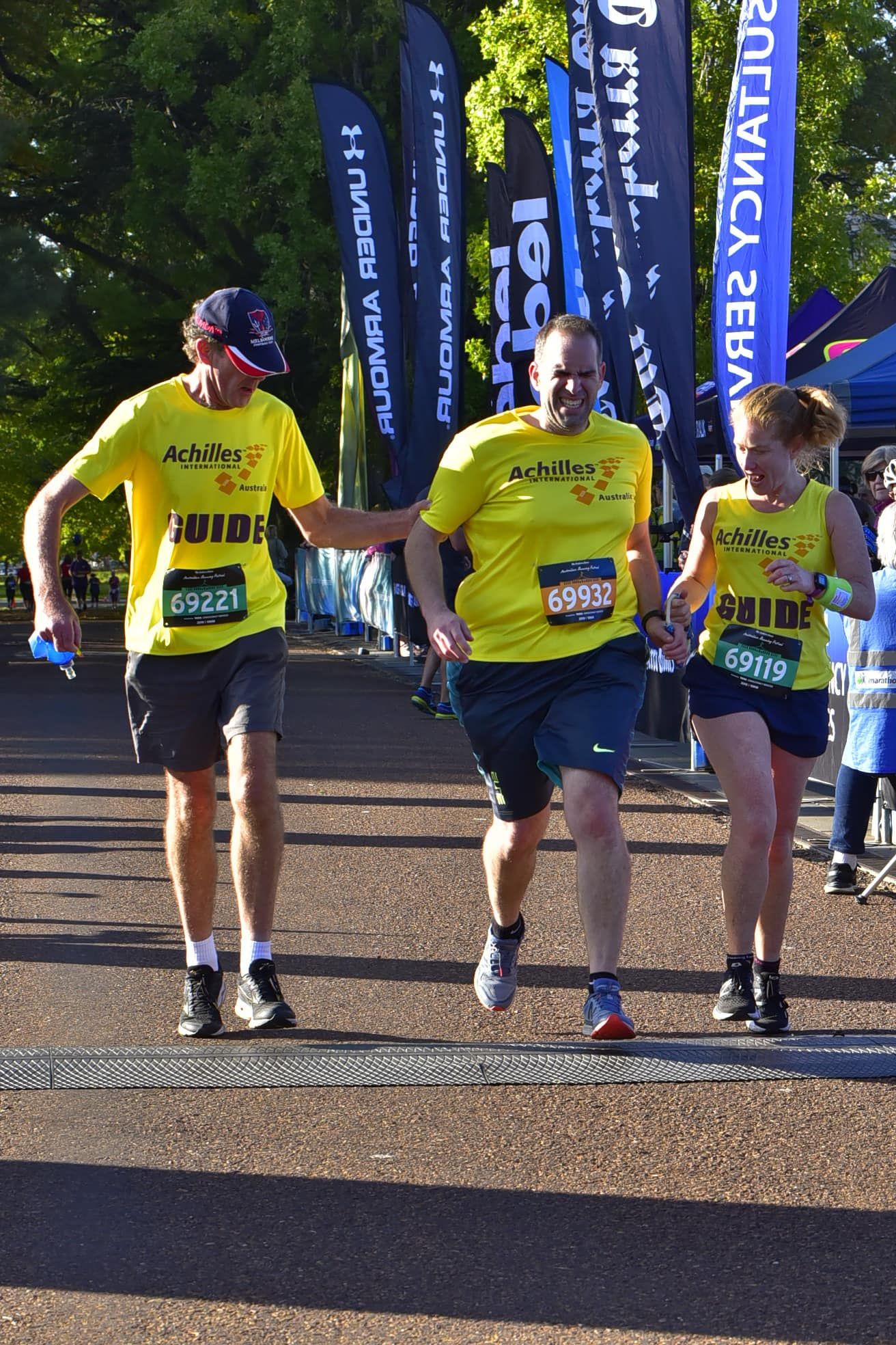 Rocco running at a race guided by a running rope/tether, flanked by another runner and his guide
