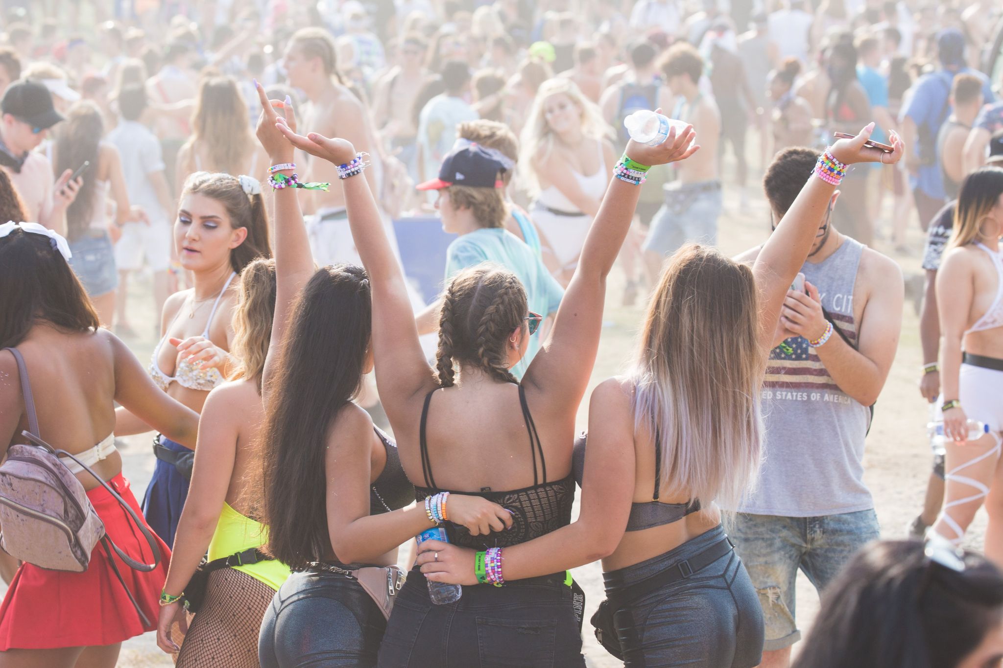 three friends posing with their arms in the air at a music festival