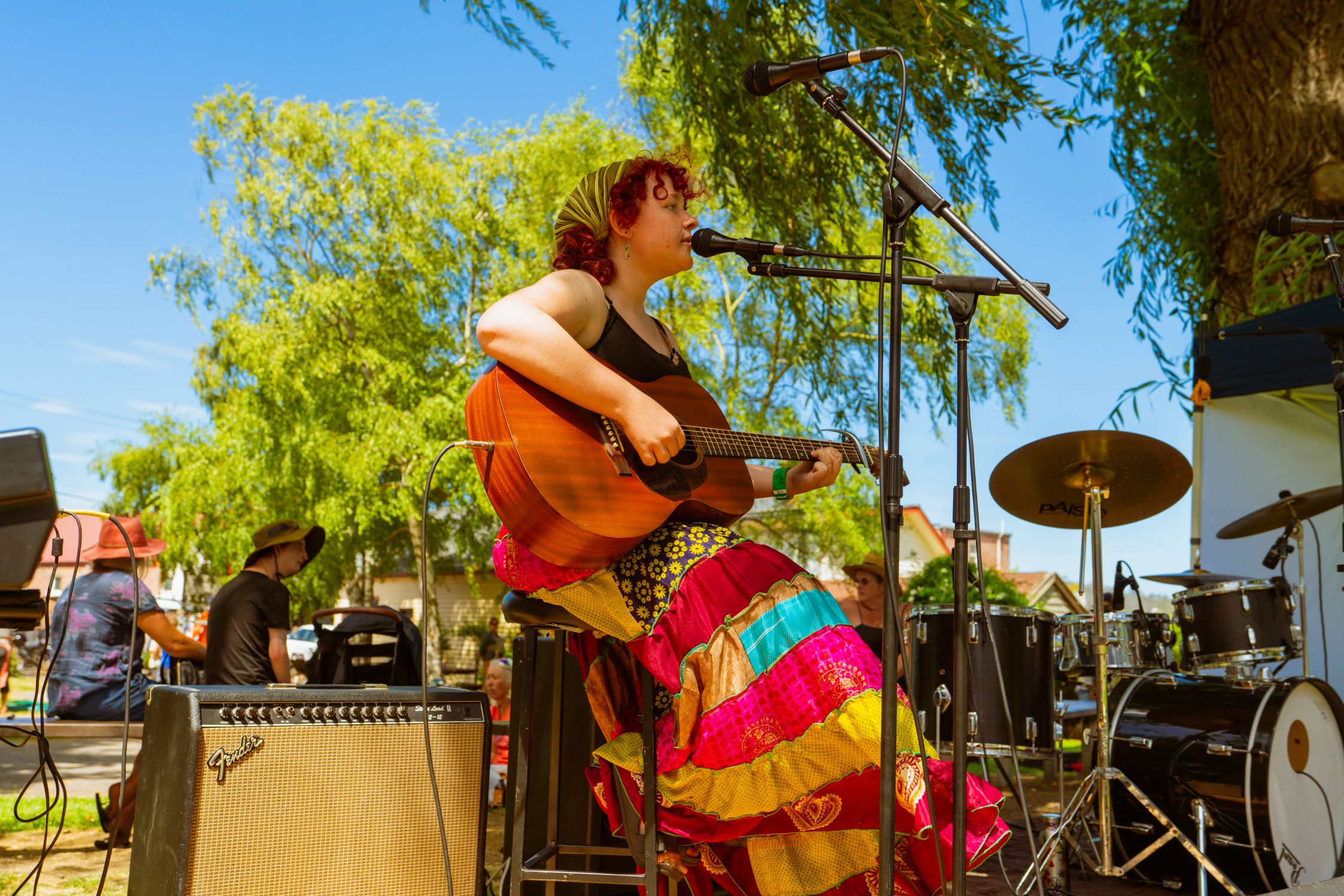 A woman in a colourful skirt playing guitar on a sunny day