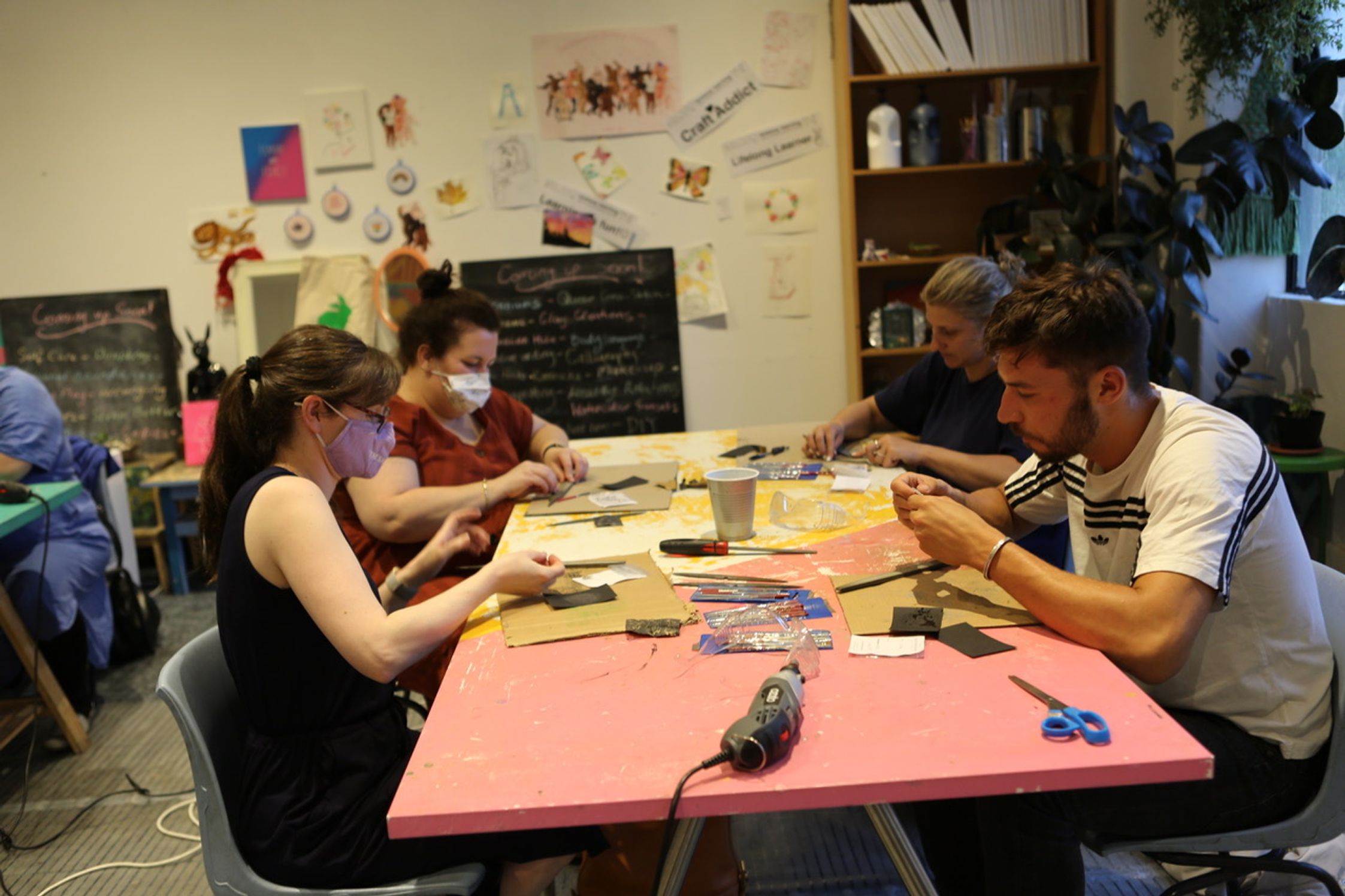 Students working on arts and crafts around a pink table