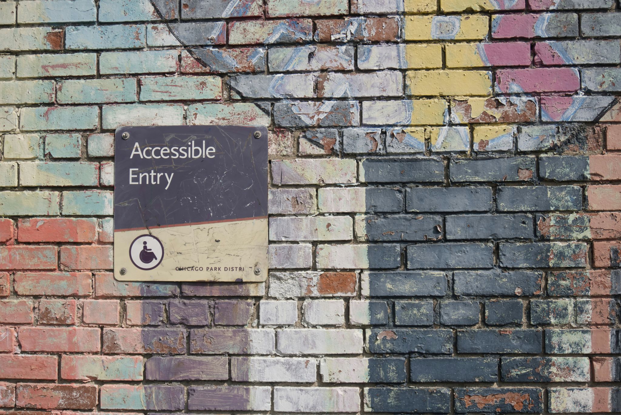 A colourful brick wall with a sign that says Accessible Entry with a wheelchair symbol