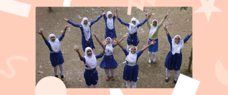 A photo of happy smiling school girls in white hijabs and blue uniforms