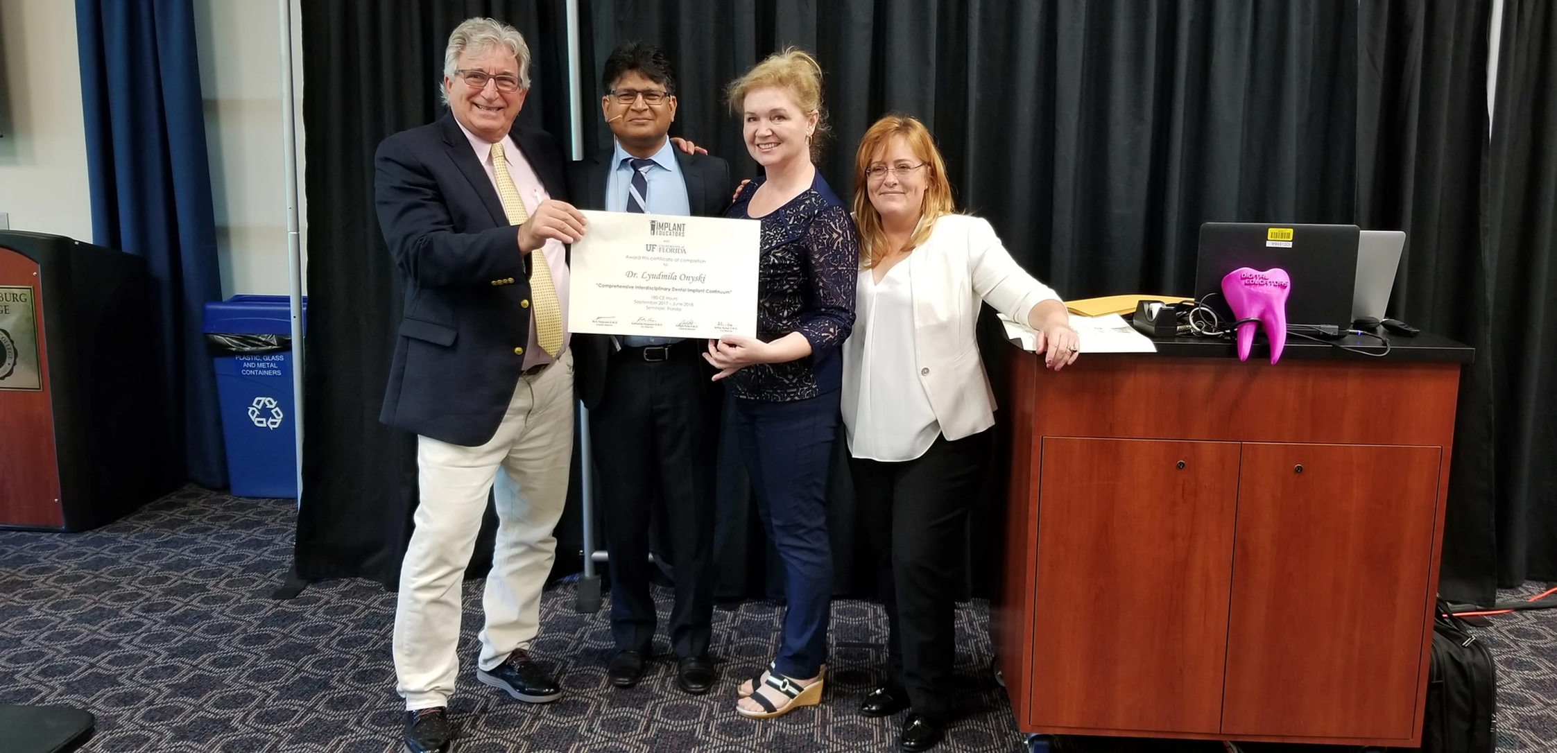 Four people posing with a certificate