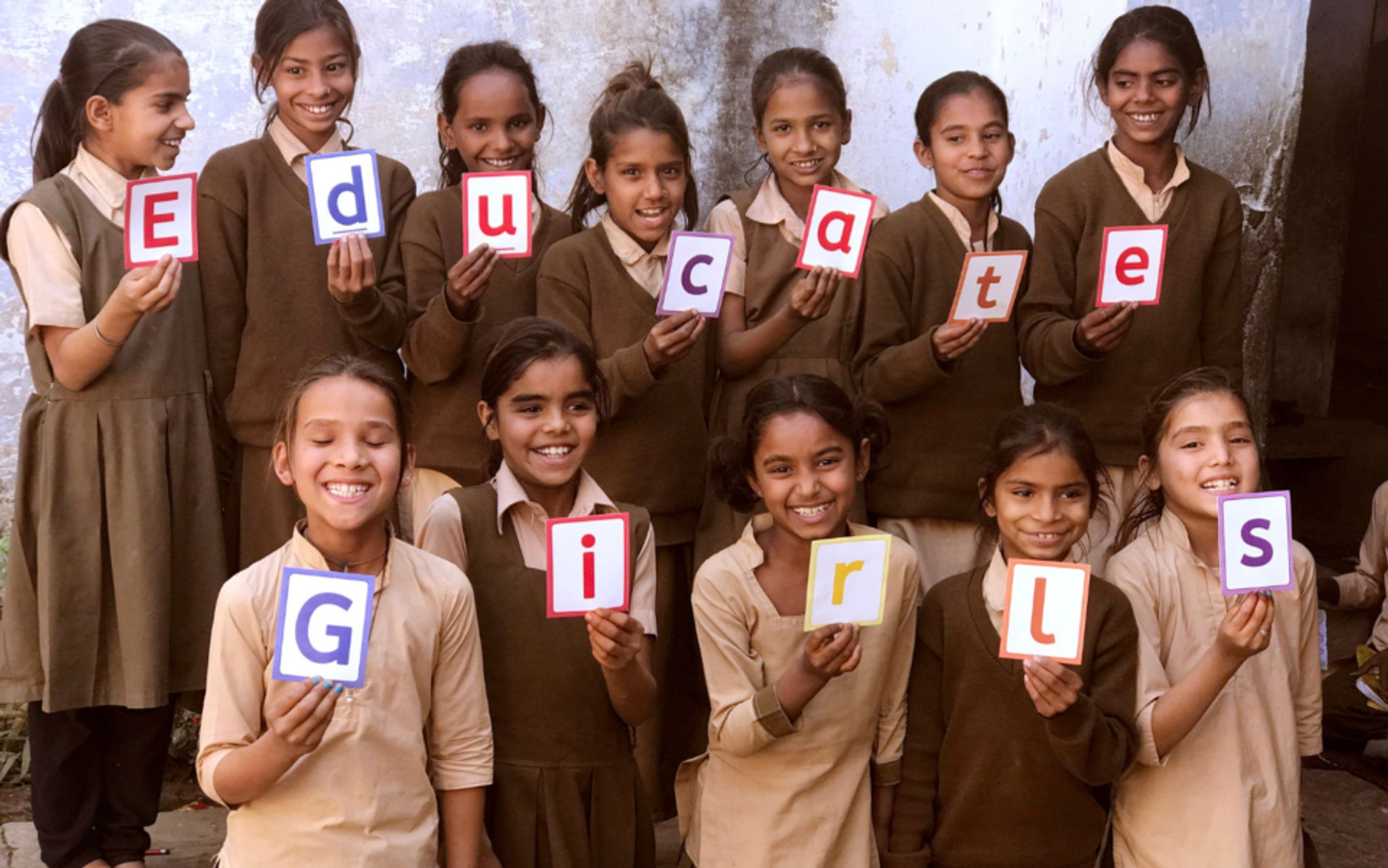 Indian girls in school uniform holding letters that spell out Educate Girls