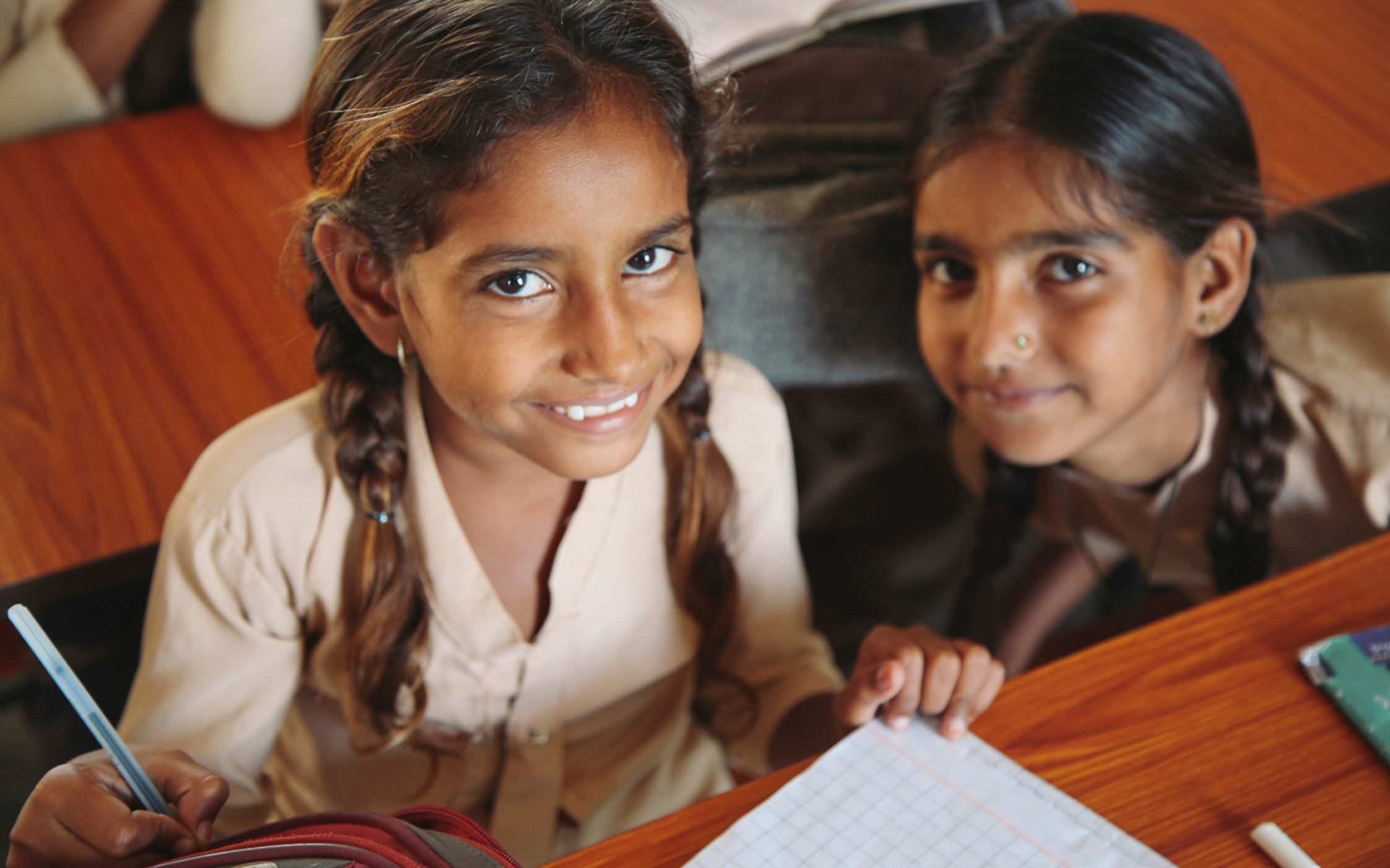 Smiling girls at their desk in school uniform