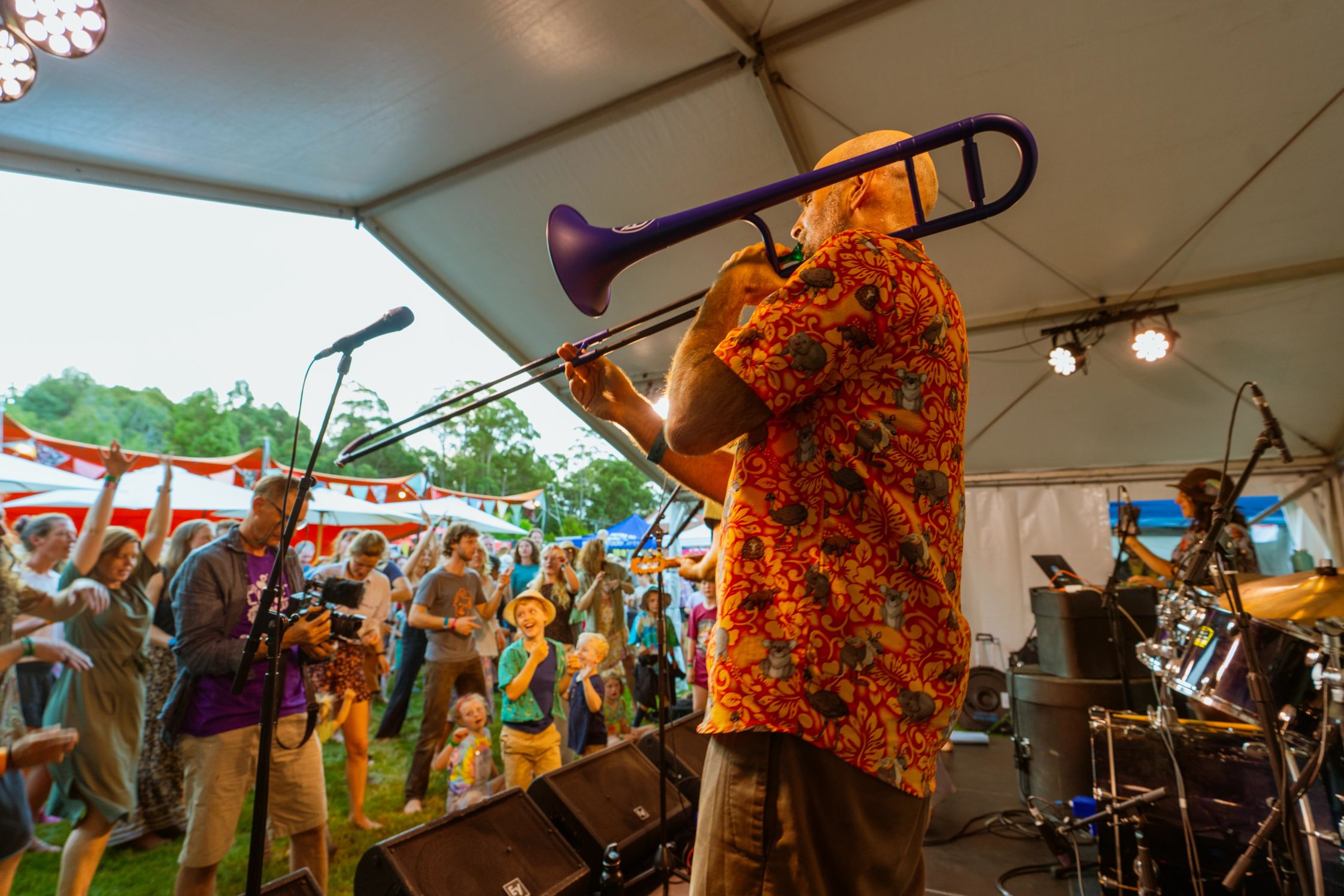 A man in a hawaiian shirt playing the trumpet to a happy audience