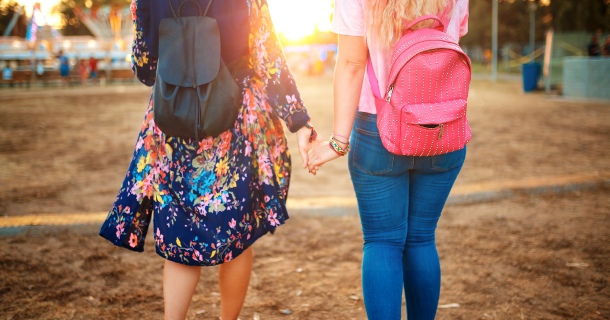 Two friends holding hands on their way into a festival