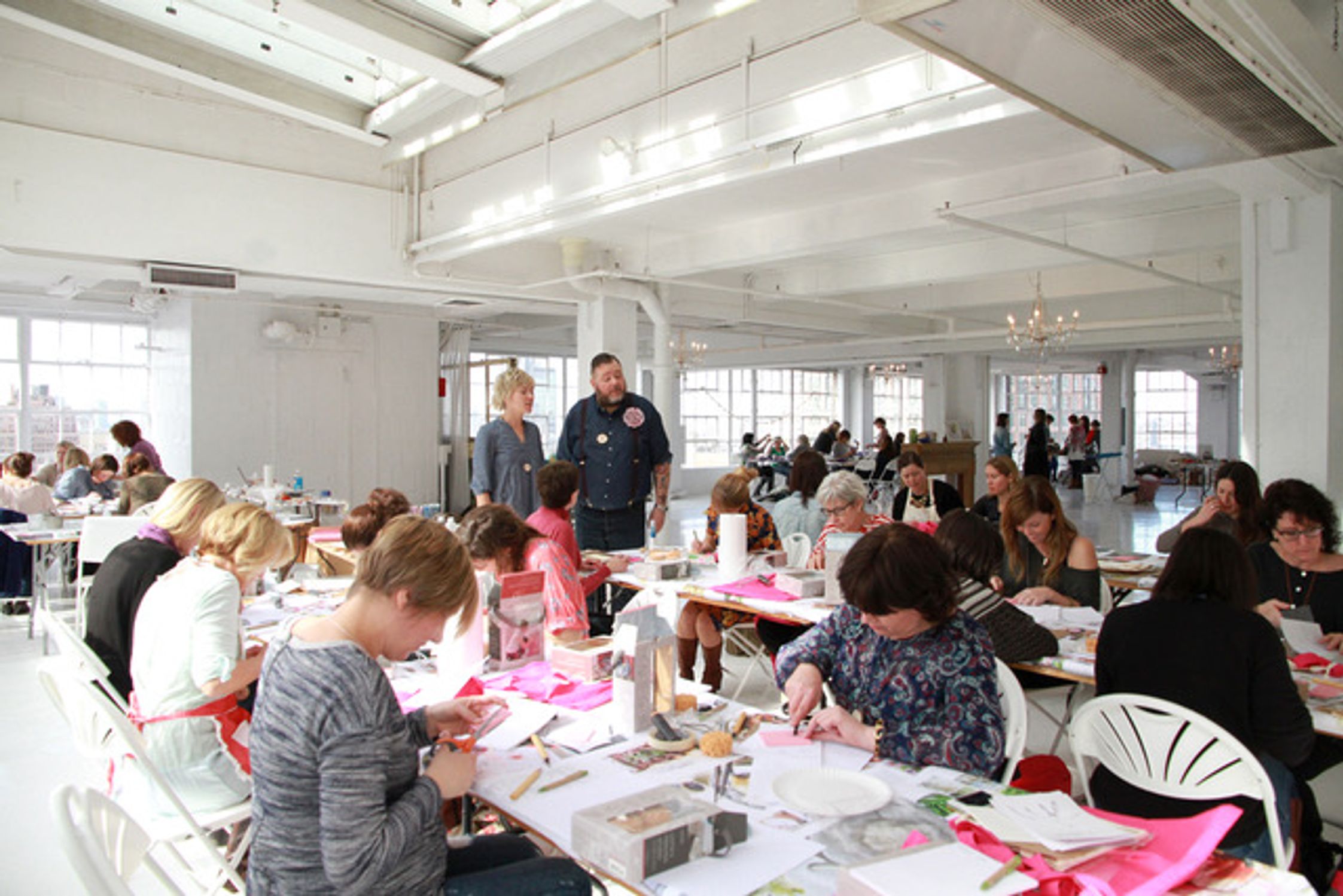 Workshop participants sitting at long tables cutting paper
