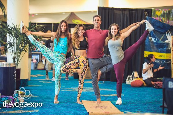 3 women and one man standing in yoga poses at the yoga expo