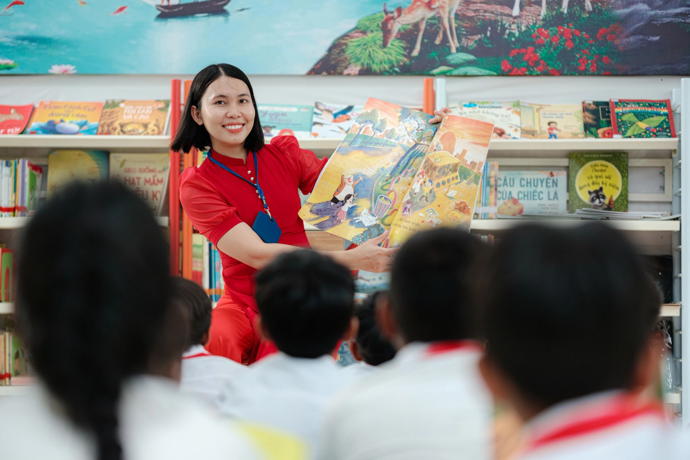 A Vietnamese teacher showing a picture book to students in the library