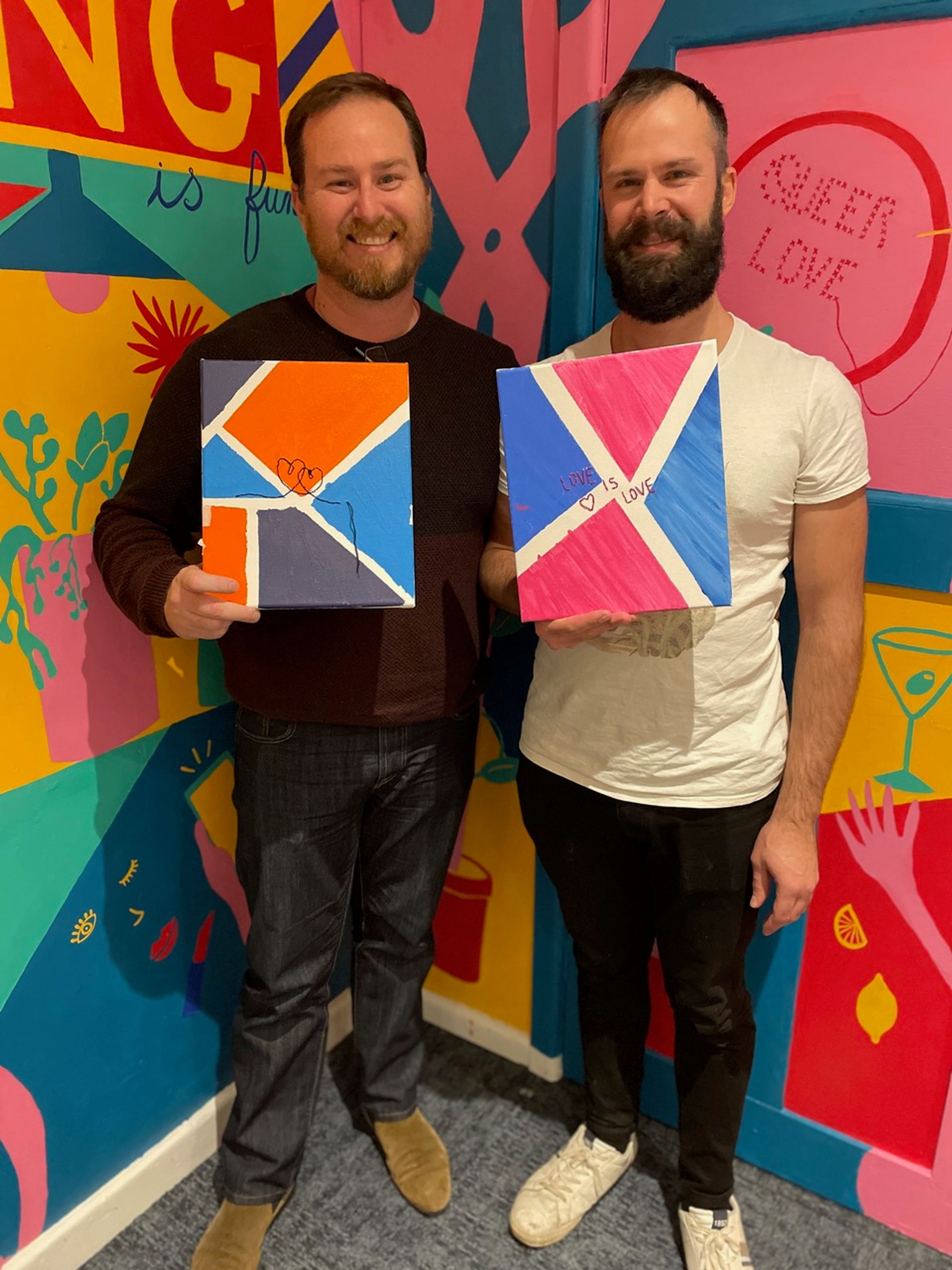 Two men holding colorful canvases