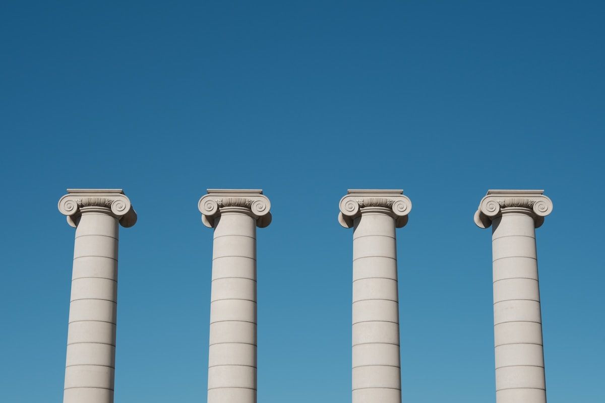 a row of white pillars against a blue sky