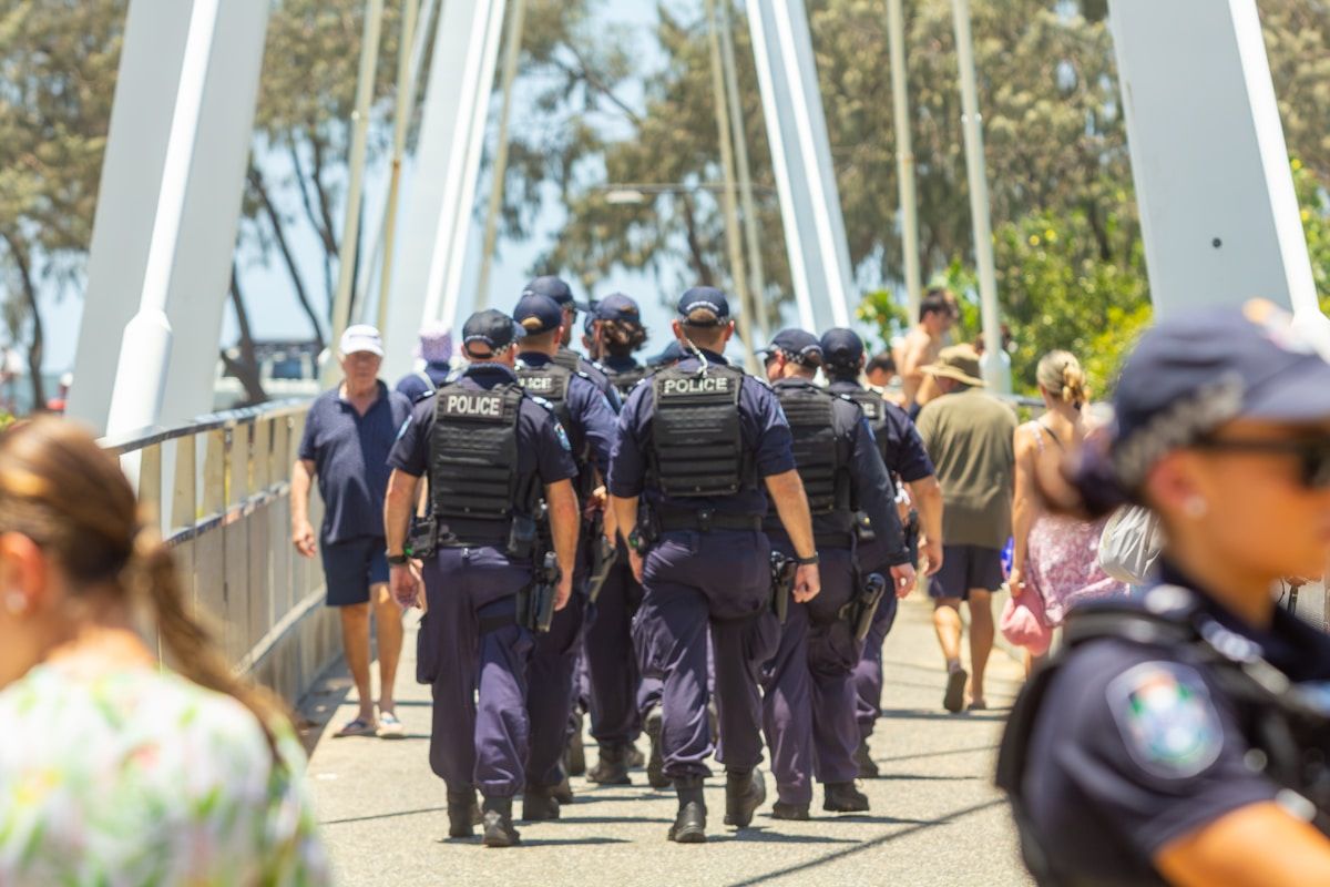 Police officers walk in formation across a bridge.